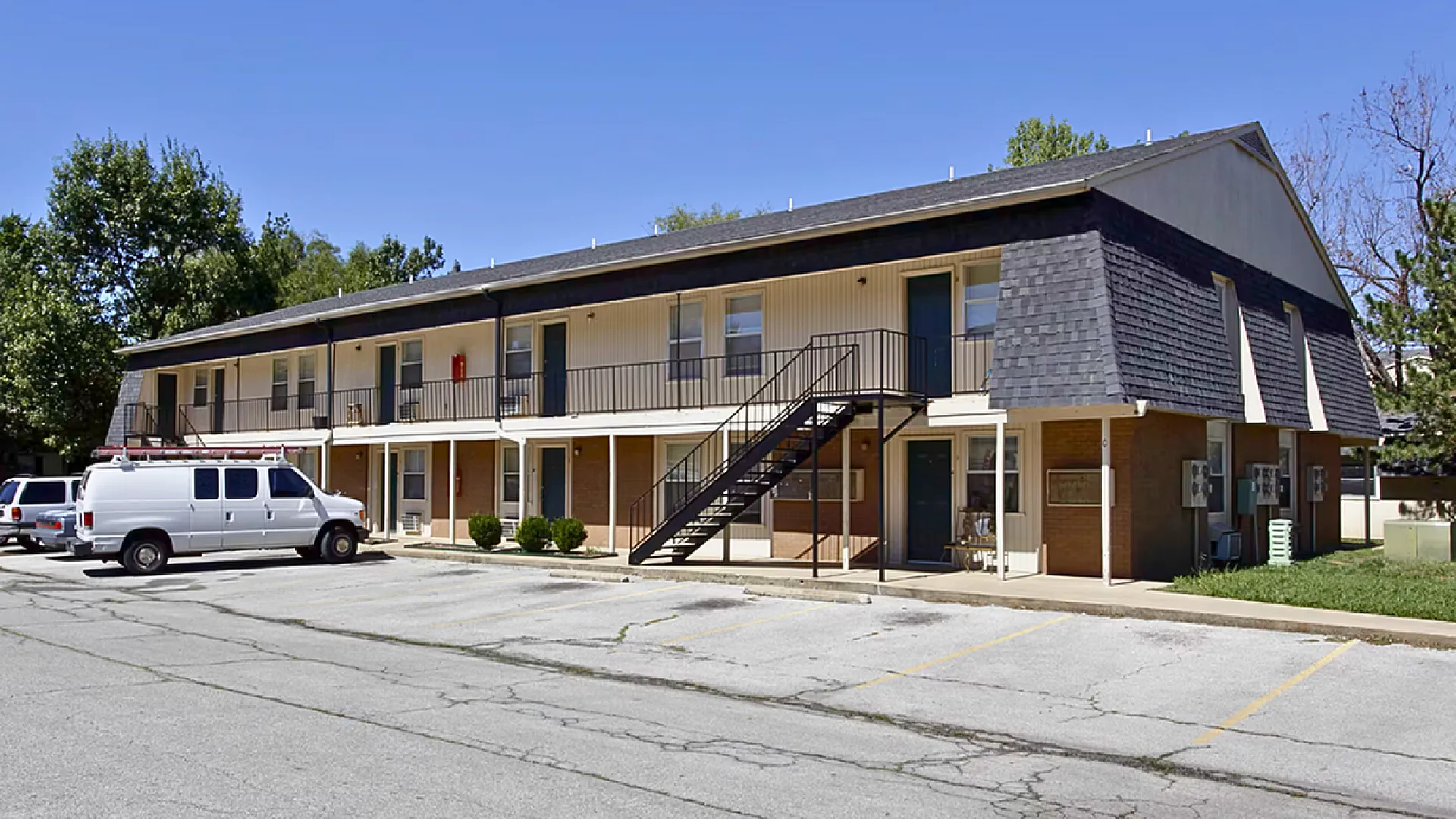 Charming two-story apartment building with convenient parking and lush greenery.