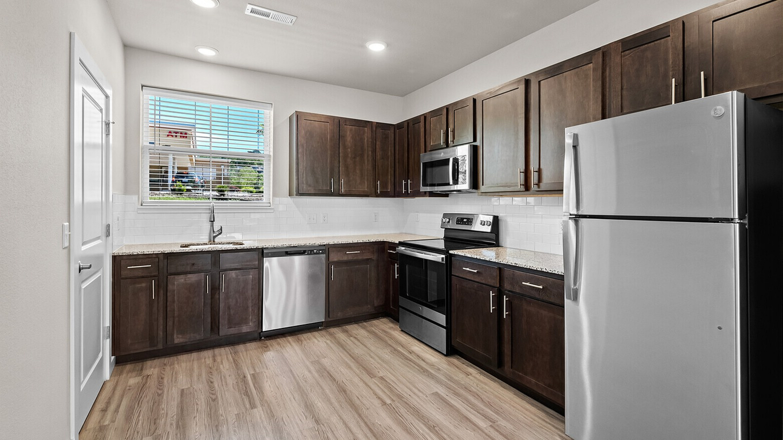 Modern kitchen with sleek stainless steel appliances, elegant dark wood cabinets, and stylish granite countertops, offering a perfect blend of functionality and aesthetics in a spacious setting.