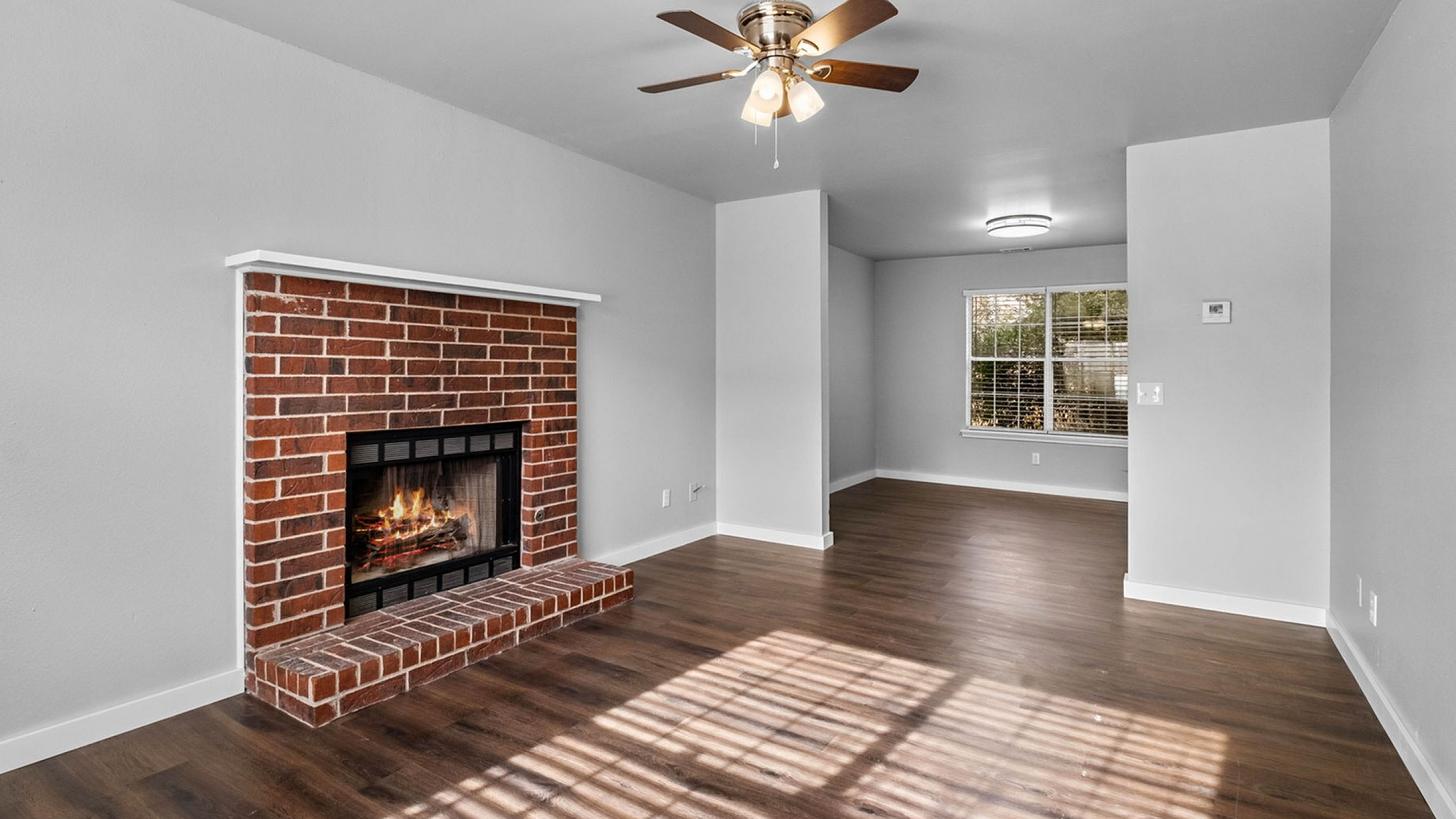 Inviting living area with elegant wood flooring and a charming brick fireplace.