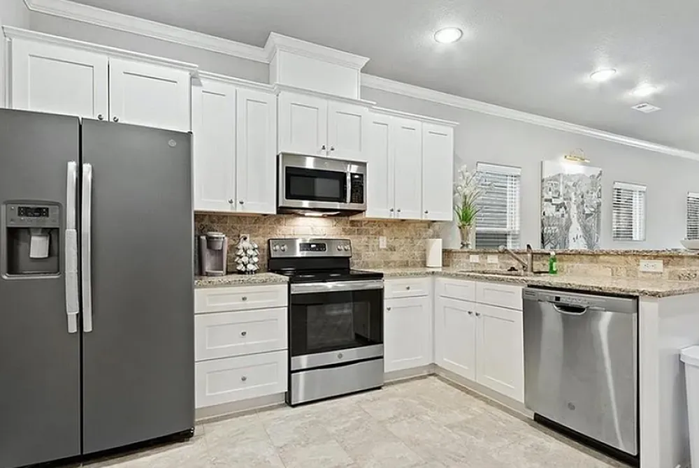 Modern kitchen with sleek stainless steel appliances, elegant white cabinetry, and warm granite countertops.