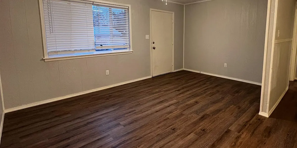 Charming living room with sleek hardwood floors, a ceiling fan, and abundant natural light, perfect for cozy living.