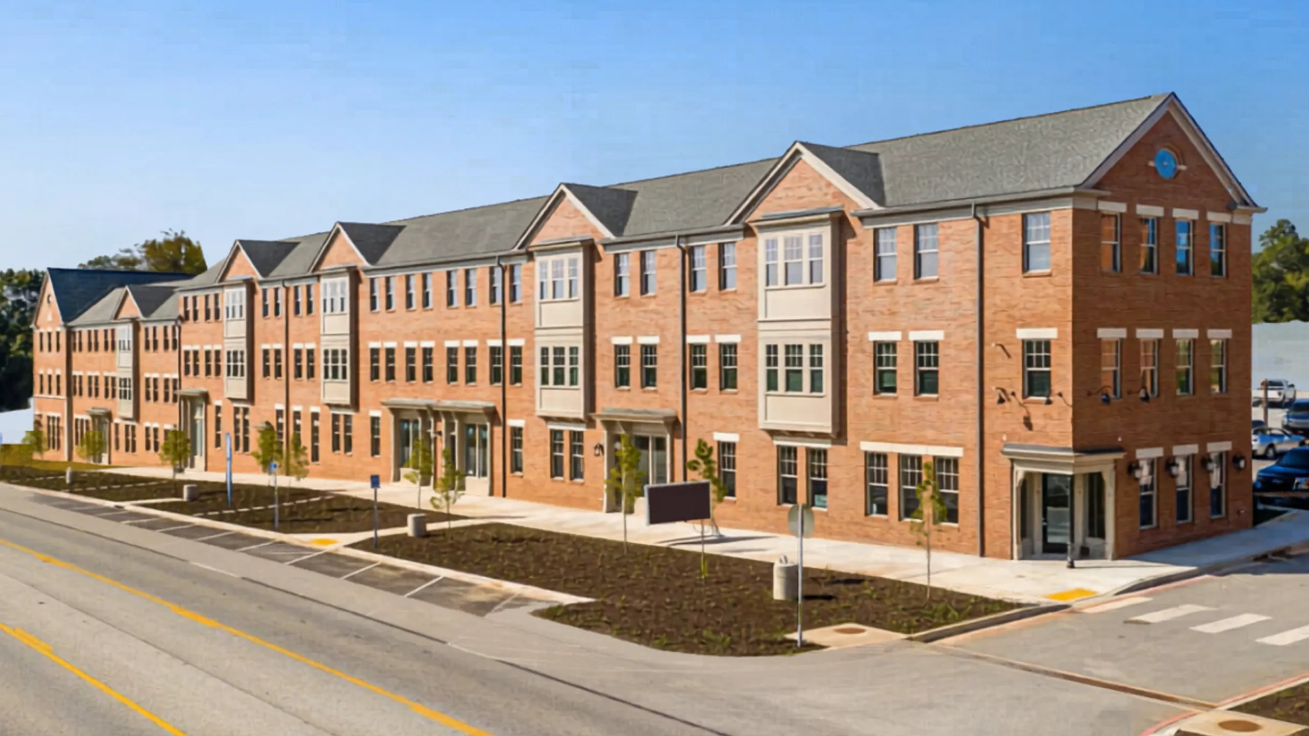Elegant row of modern red-brick apartments with large windows and charming architectural details along a well-maintained street.