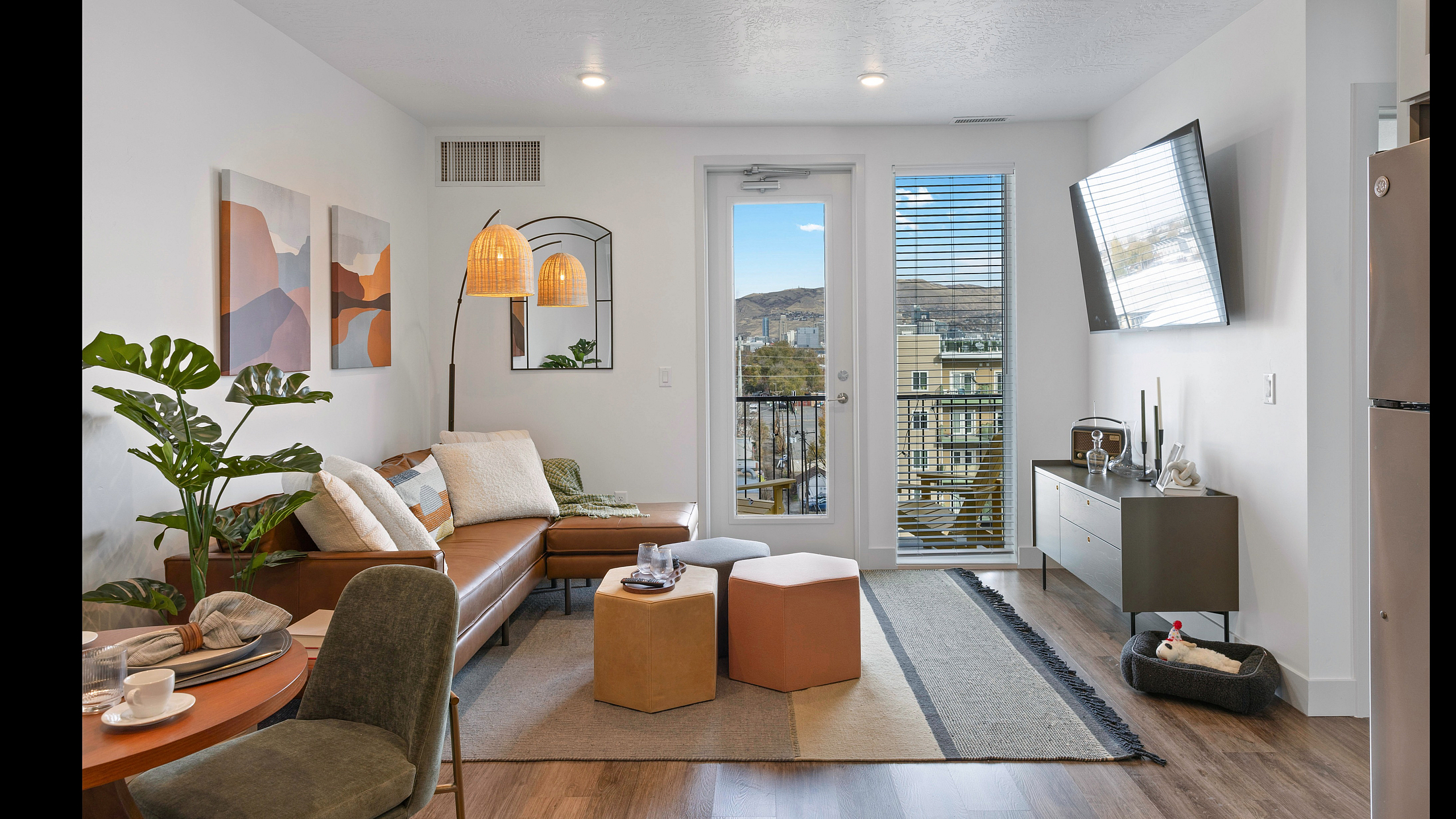 Chic modern living room with a cozy brown leather sofa, stylish decor, and a balcony view of the cityscape. Perfect space for relaxation and entertaining.