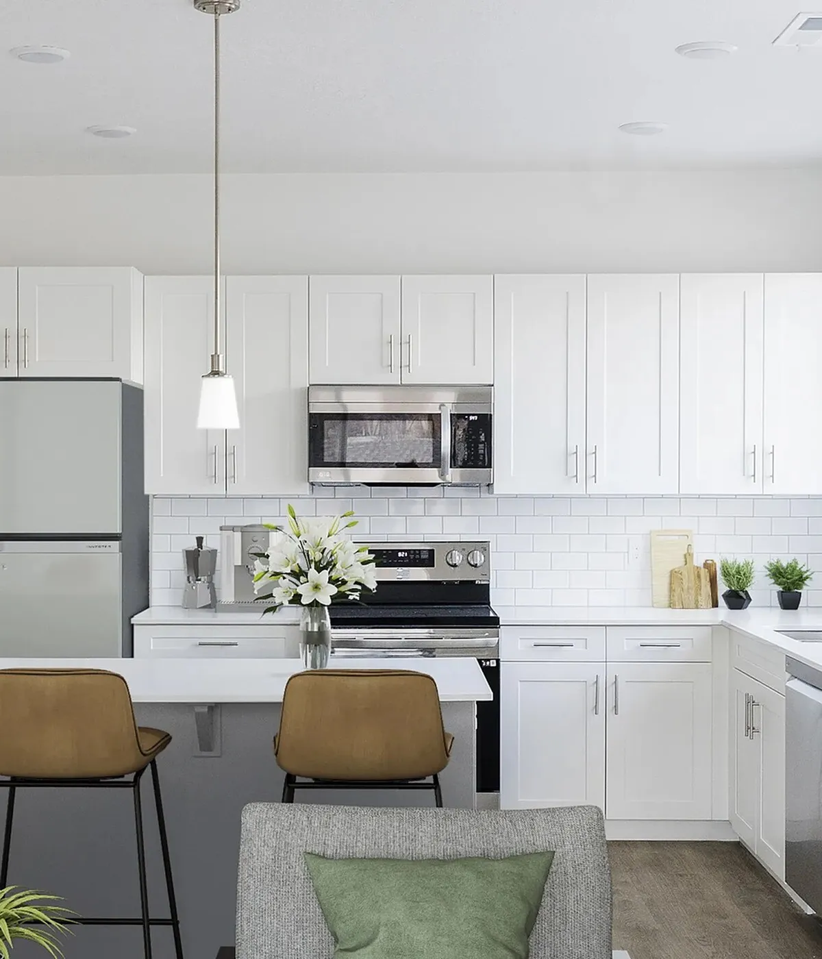 White kitchen with quartz island, bar seating and stainless steel appliances at Erin Hills Estates