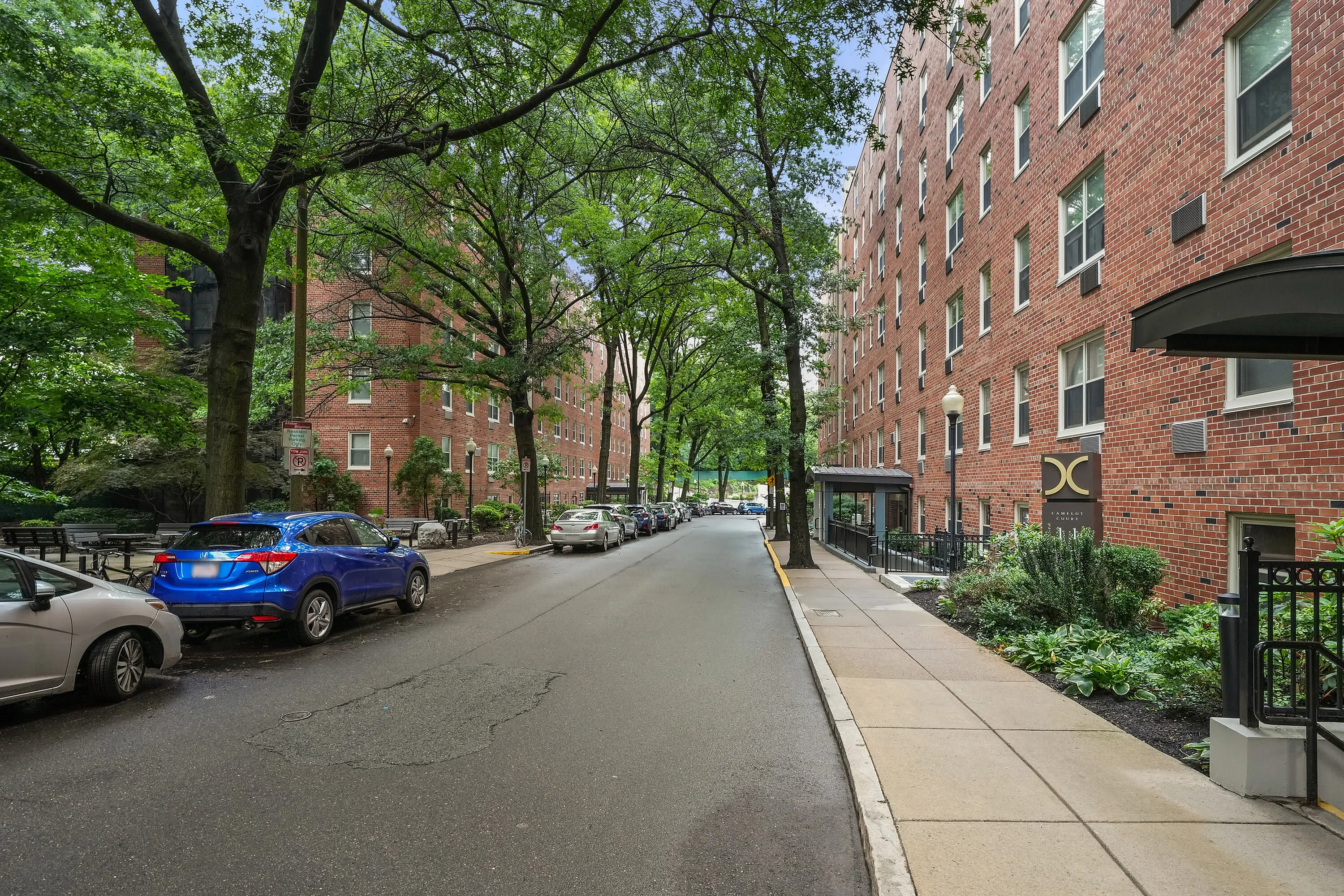 Charming street view with tree-lined walkways and classic brick apartment buildings, offering a serene urban living environment.