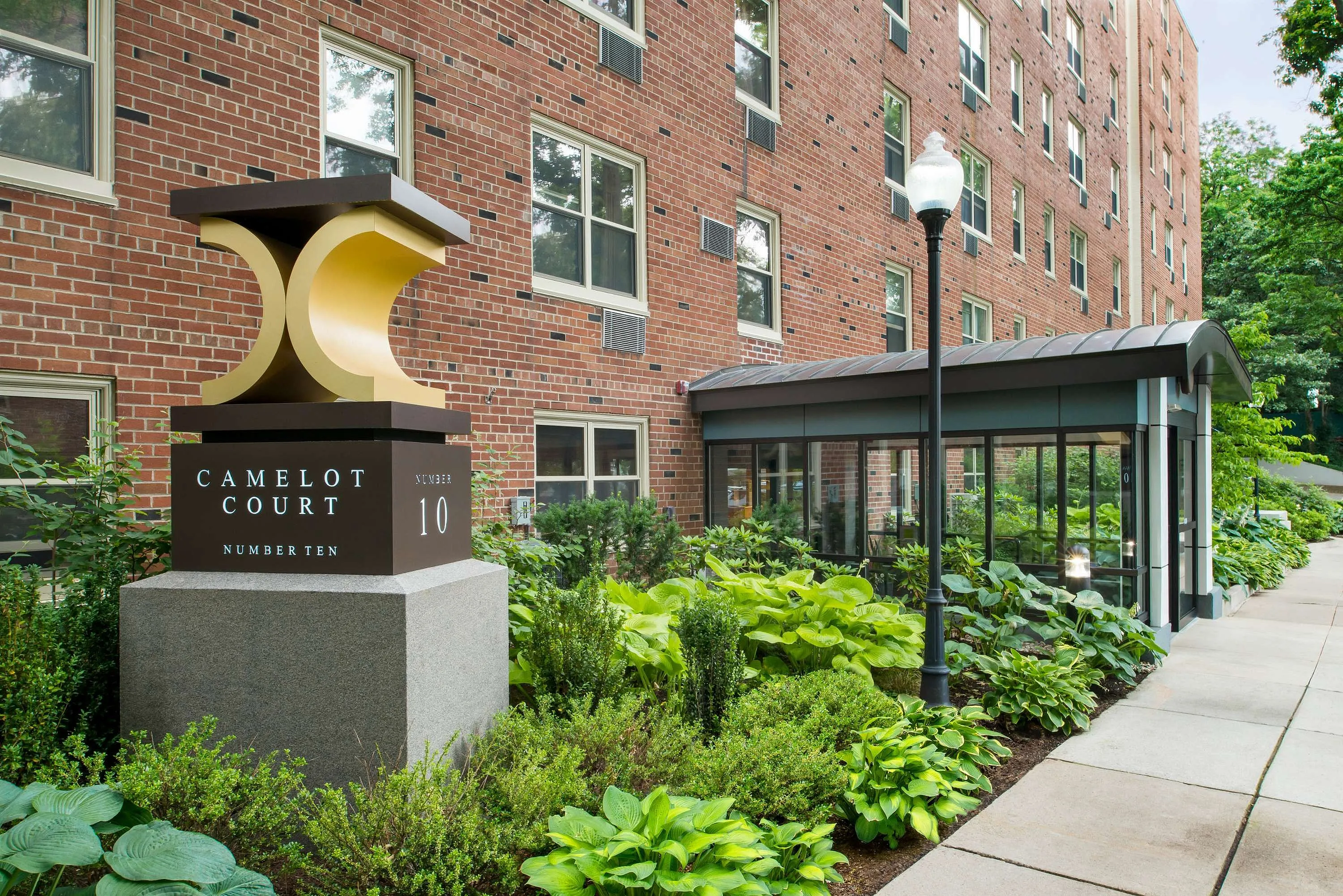 Charming apartment complex with lush landscaping and modern entryway at Camelot Court, Number Ten.