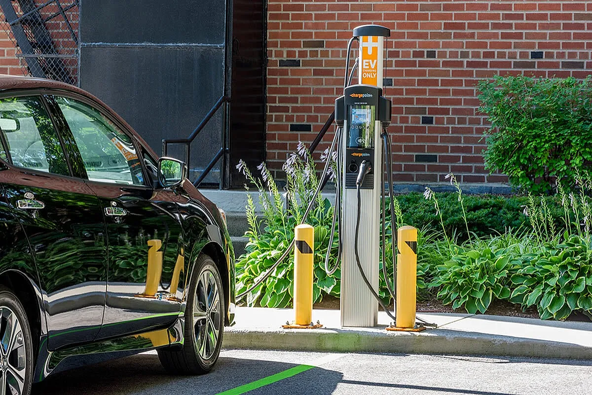 Modern electric vehicle charging station in a lush, green urban setting, highlighting eco-friendly amenities.