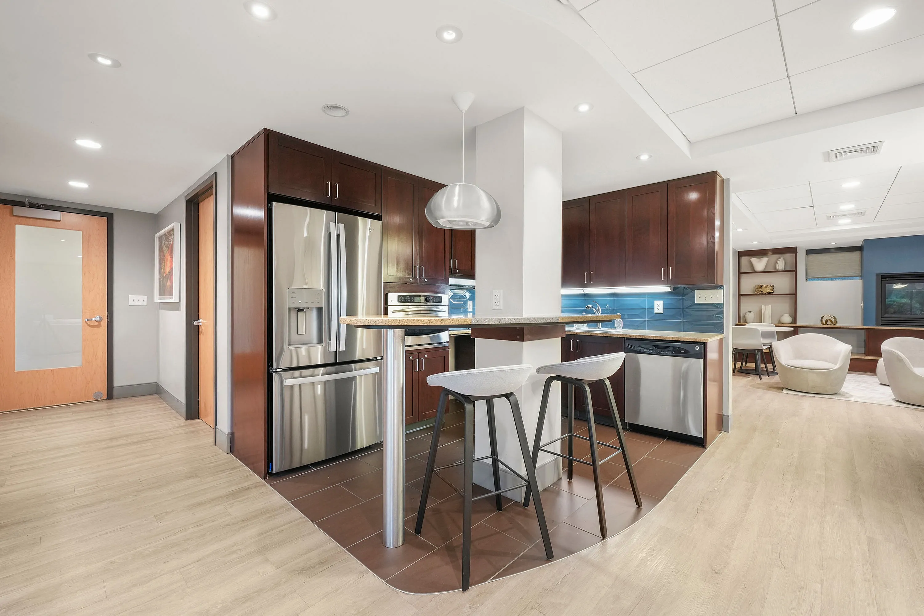 Contemporary open-concept kitchen with stainless steel appliances, sleek bar seating, and elegant wood cabinetry.