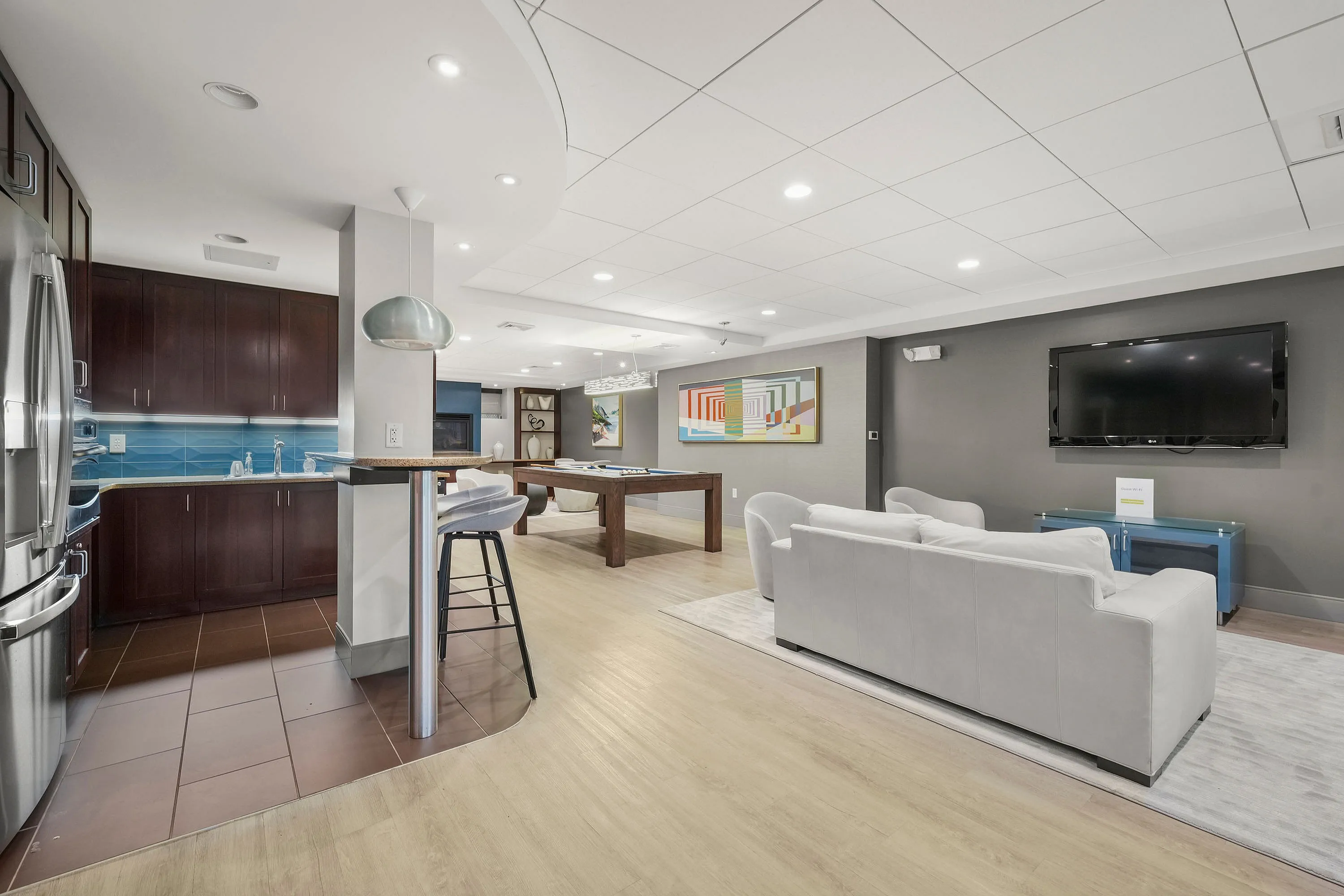Stylish modern apartment with open-concept living area, featuring a sleek kitchen, elegant seating, and a pool table for entertainment.