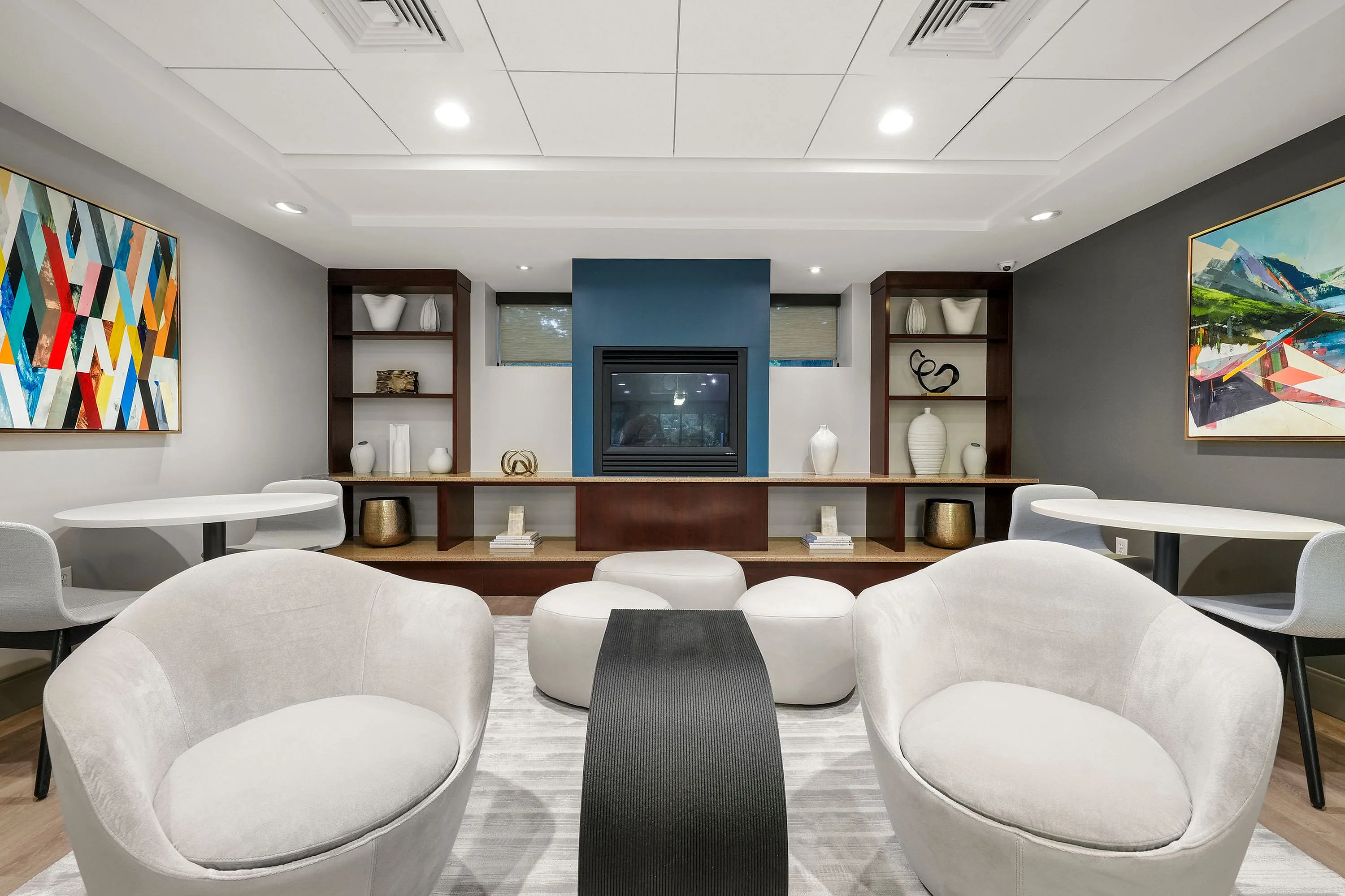 Elegant lounge area featuring modern armchairs, abstract artwork, and a sleek fireplace, perfect for relaxing in style.