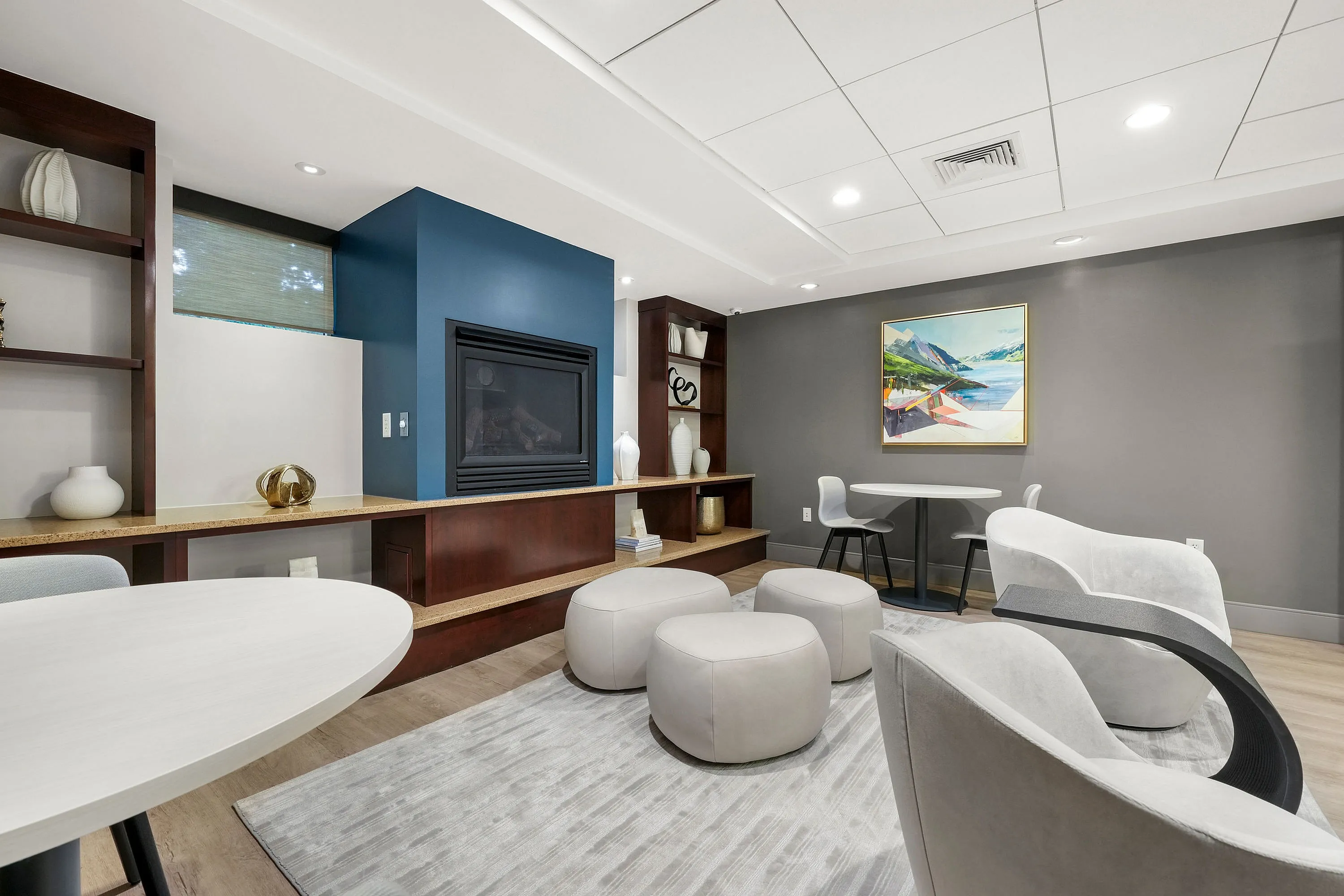 Chic apartment lounge featuring modern seating, stylish decor, and a cozy fireplace with vibrant artwork on the wall.