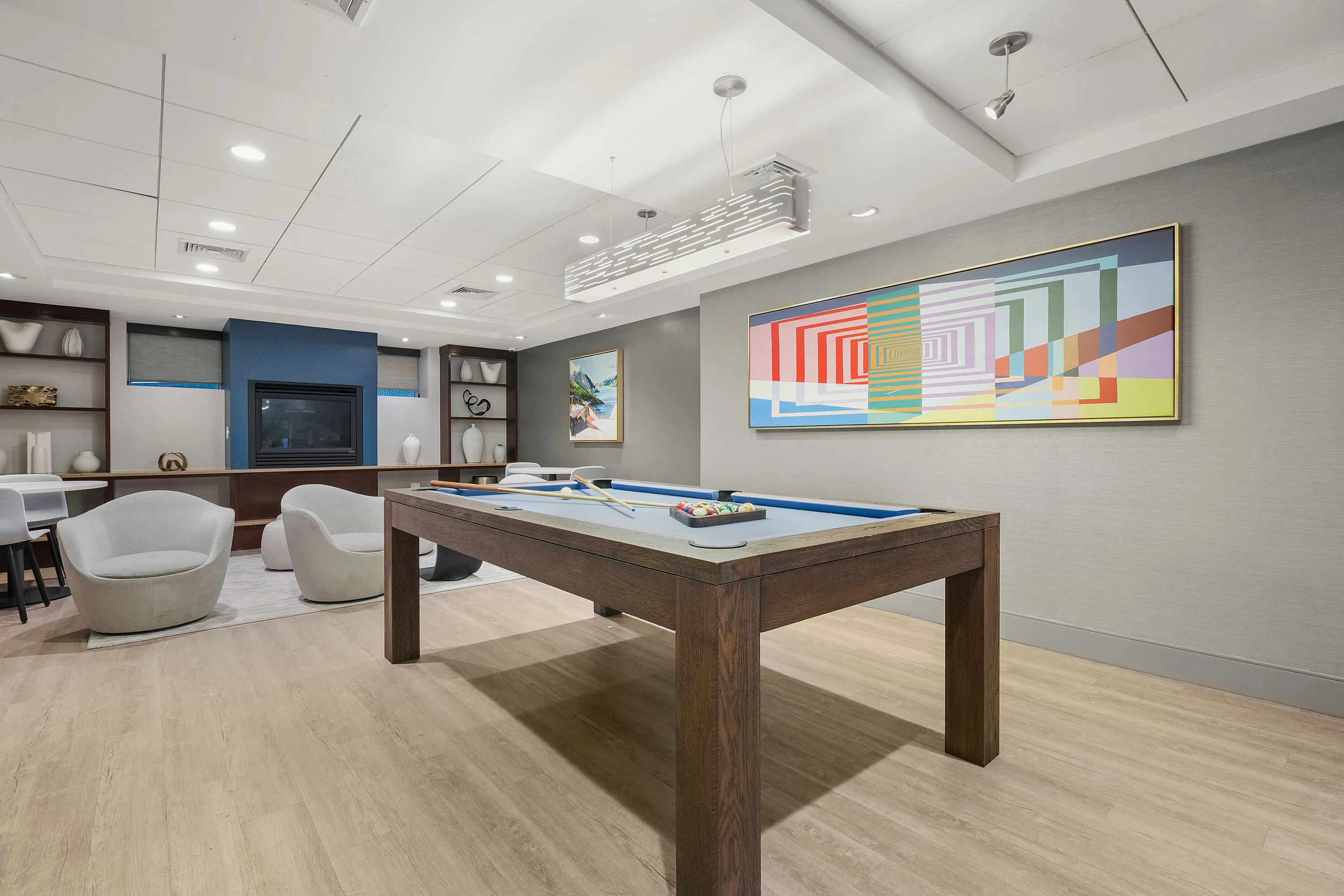 Contemporary recreation room featuring a stylish billiards table, modern artwork, and cozy seating, perfect for entertainment and relaxation.