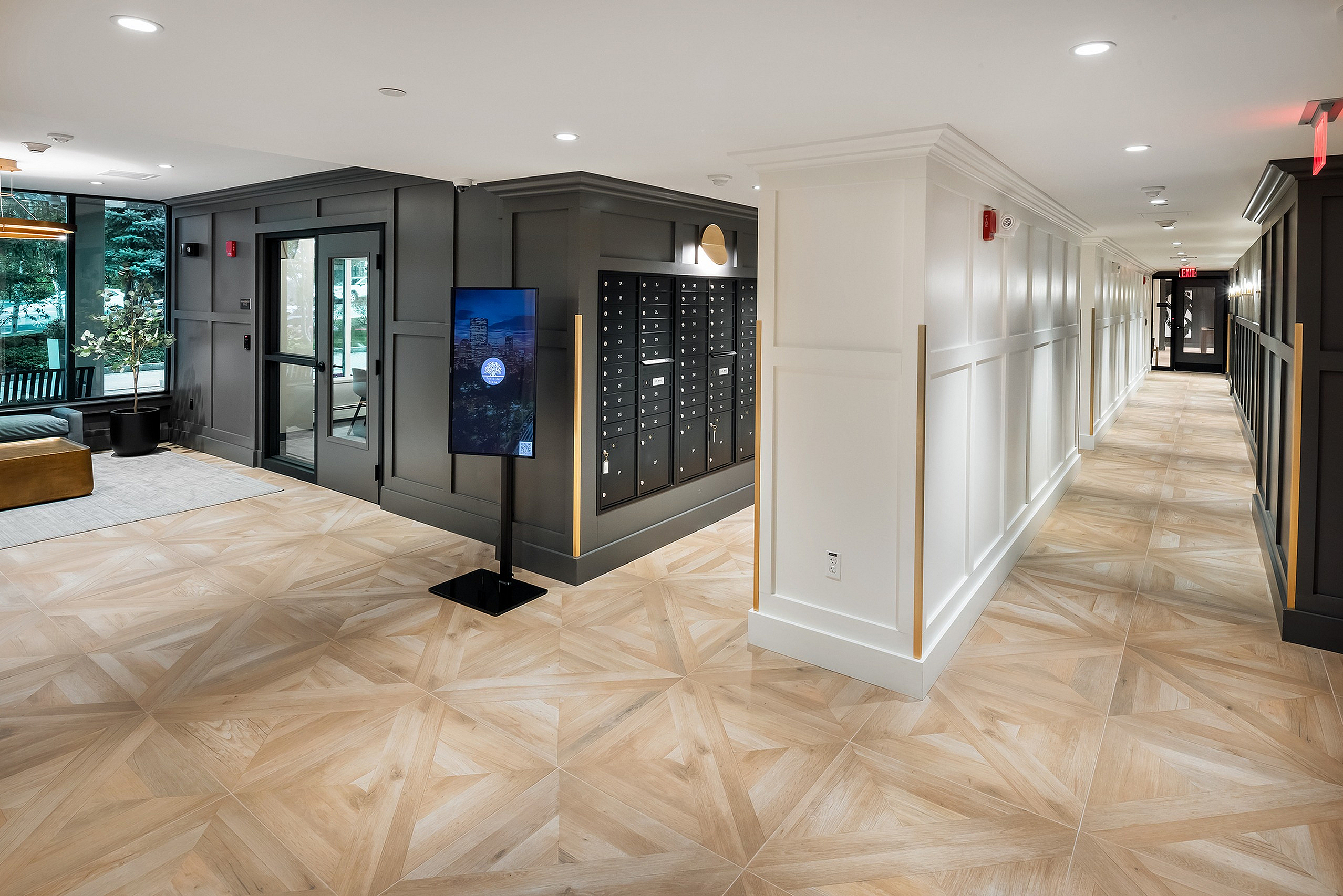 Elegant apartment lobby featuring modern design with stylish wood-patterned tiles, sleek black mailboxes, and comfortable seating area.