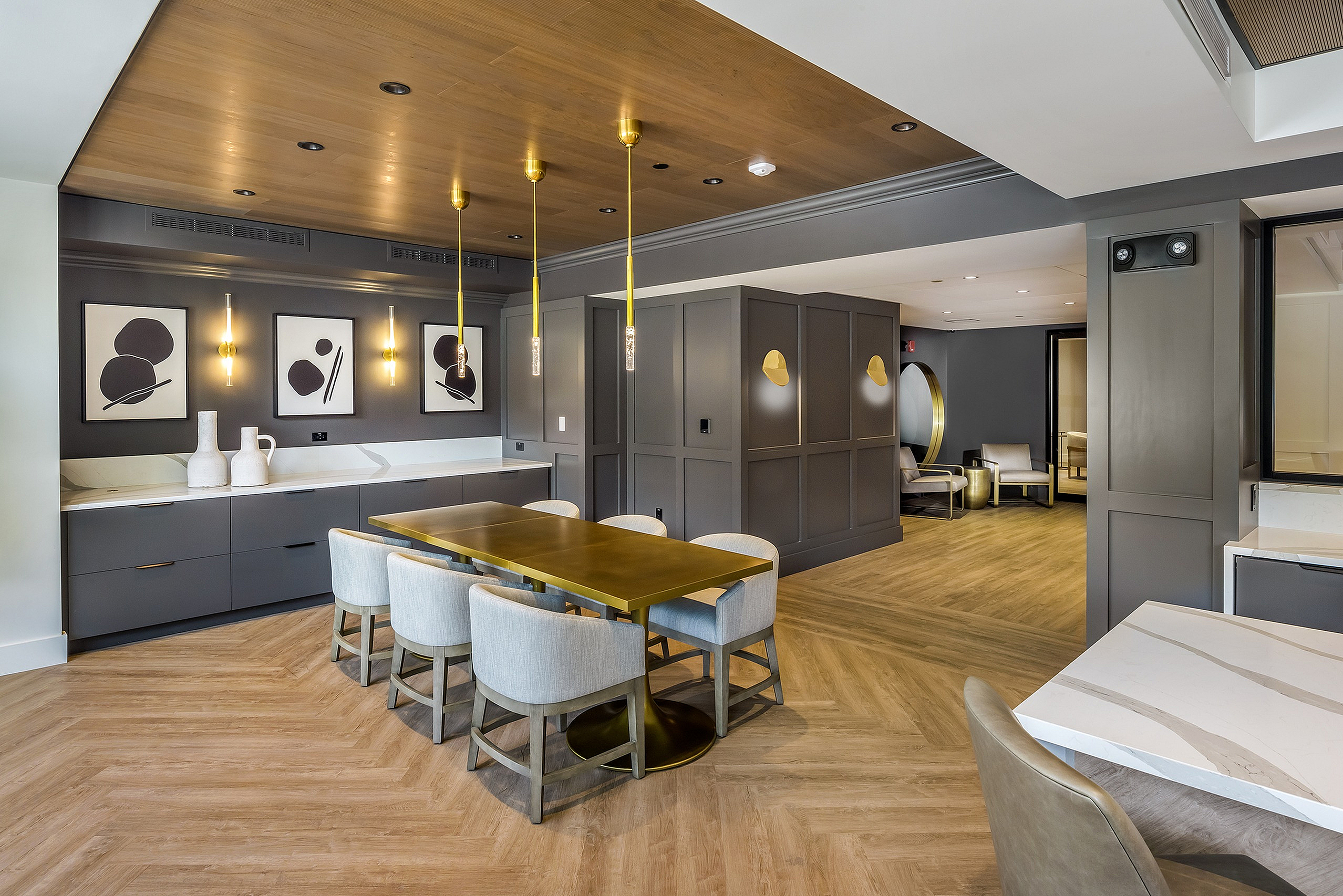 Elegant dining area with chic wooden flooring and modern pendant lighting, featuring a stylish dining table and contemporary artwork on the walls.
