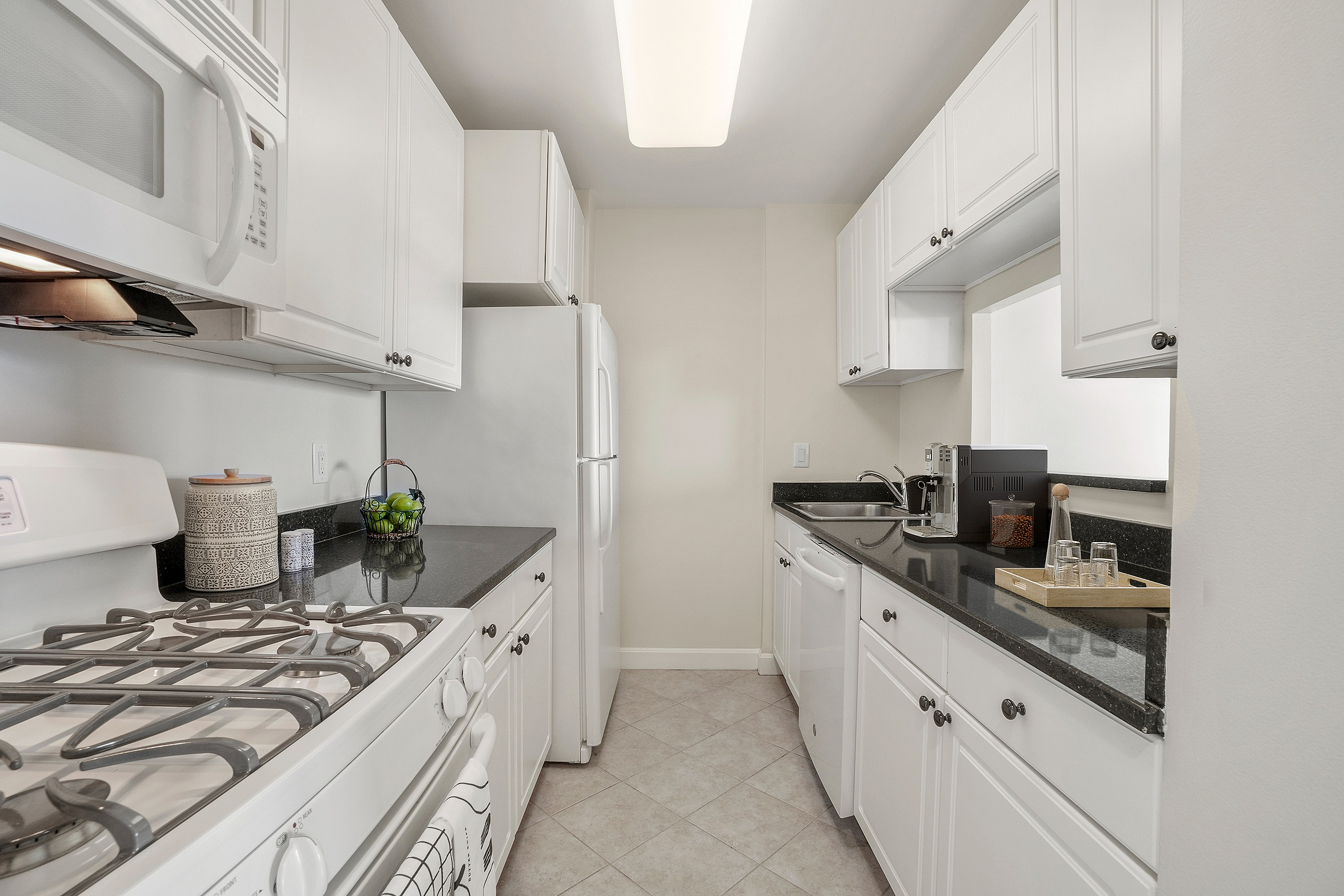 Charming modern kitchen with sleek black countertops, white cabinetry, and state-of-the-art appliances offering a bright and functional cooking space.