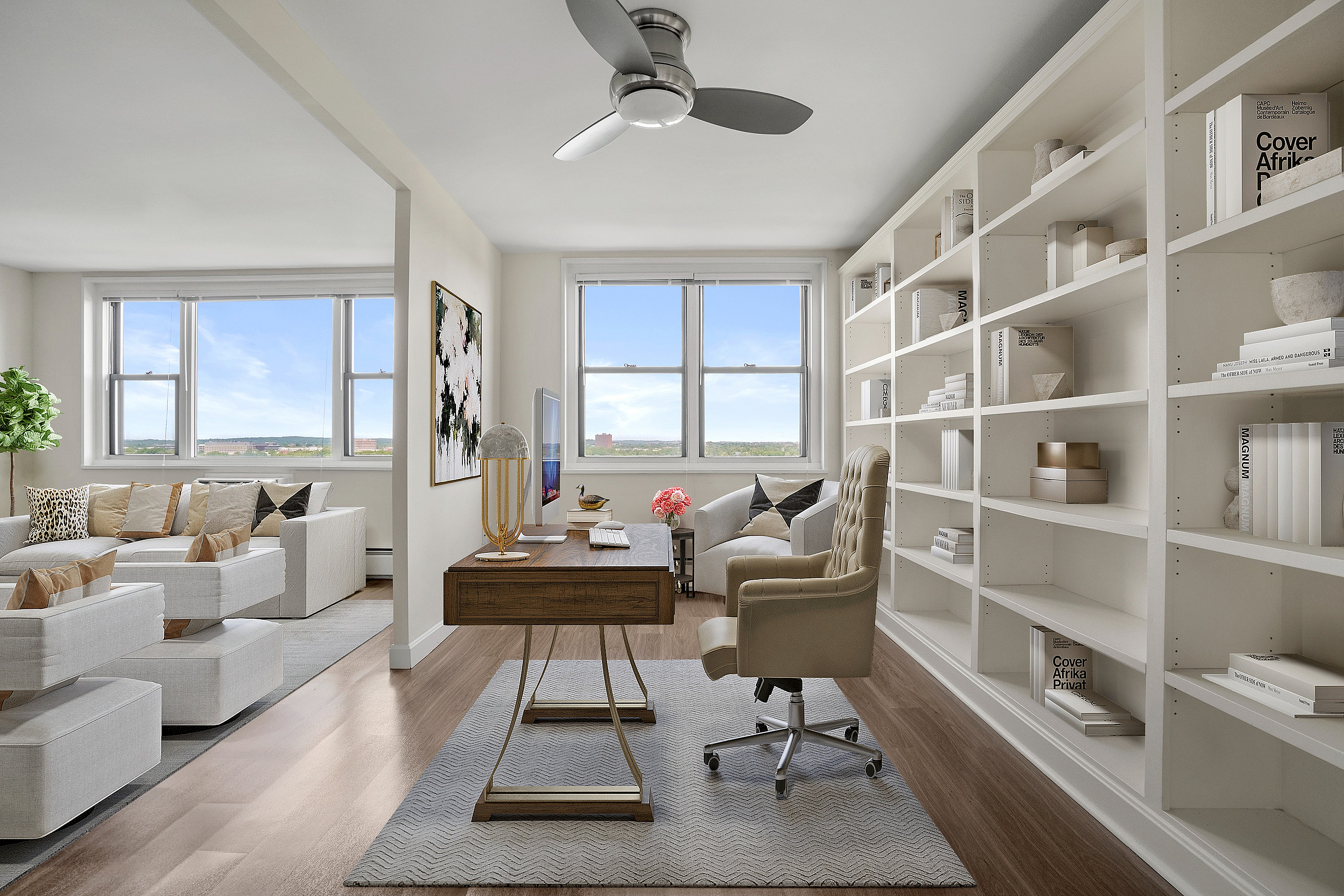 Luxurious open-space apartment with elegant home office, built-in bookshelves, and bright living area overlooking a stunning view.