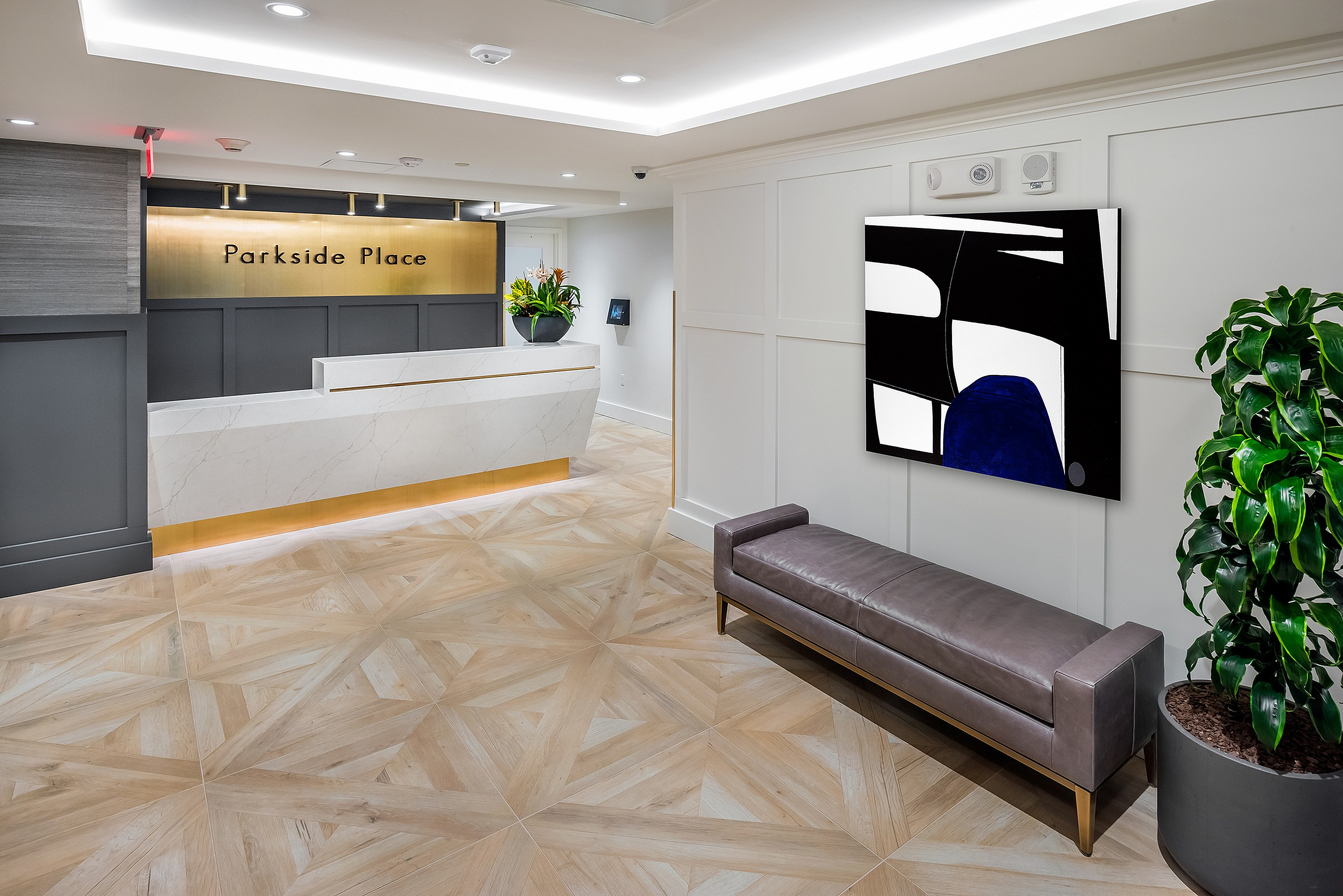 Elegant lobby of Parkside Place featuring a sleek marble reception desk, modern seating, and vibrant artwork against a sophisticated backdrop.