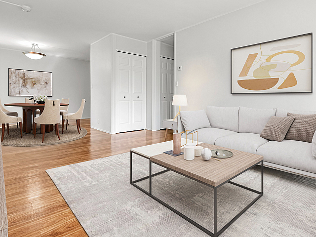 Chic modern living room with cozy light grey sofa, elegant coffee table, and vibrant wood flooring leading to a sophisticated dining area with plush beige chairs and contemporary artwork.
