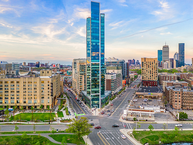 Stunning urban skyline view featuring a modern high-rise building surrounded by vibrant city architecture under a pastel sunset sky.