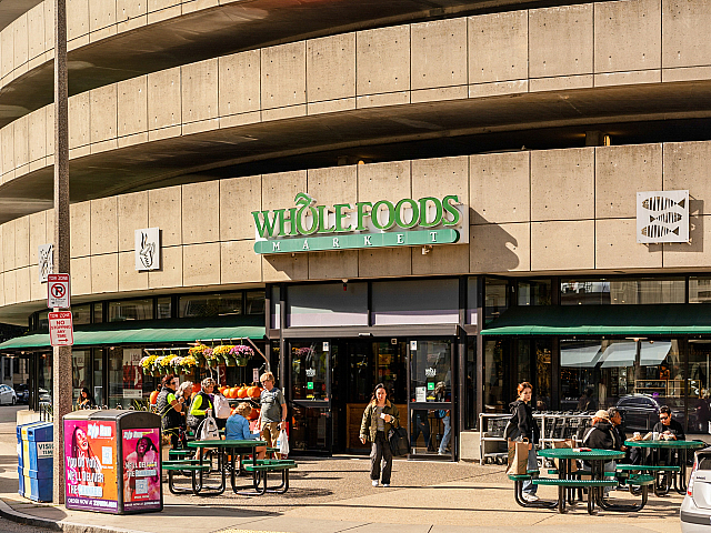Vibrant Whole Foods Market entrance with outdoor seating and shoppers enjoying a sunny day.