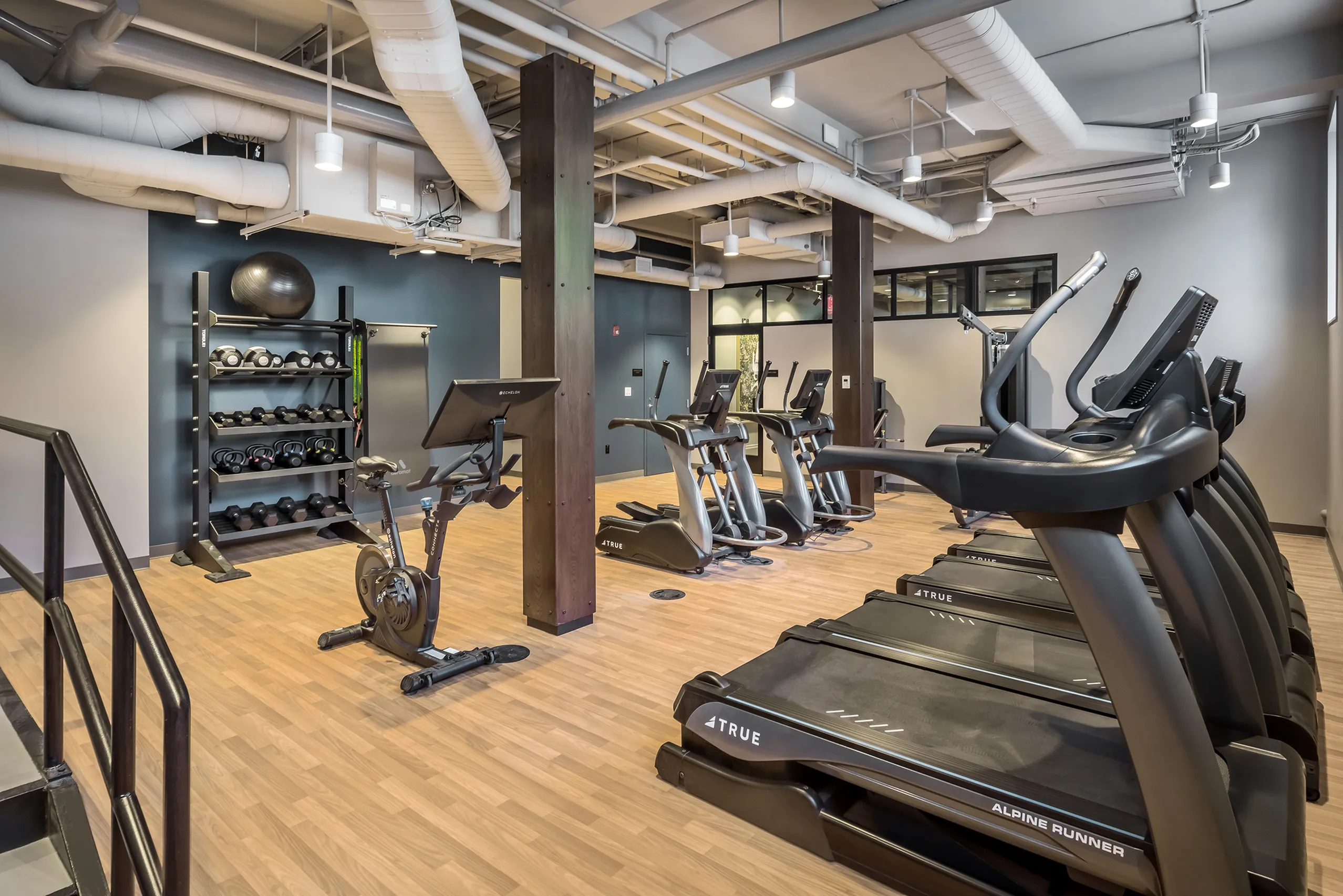 Modern fitness center featuring state-of-the-art exercise equipment, including treadmills, stationary bikes, and a variety of weights, set in a sleek industrial design.