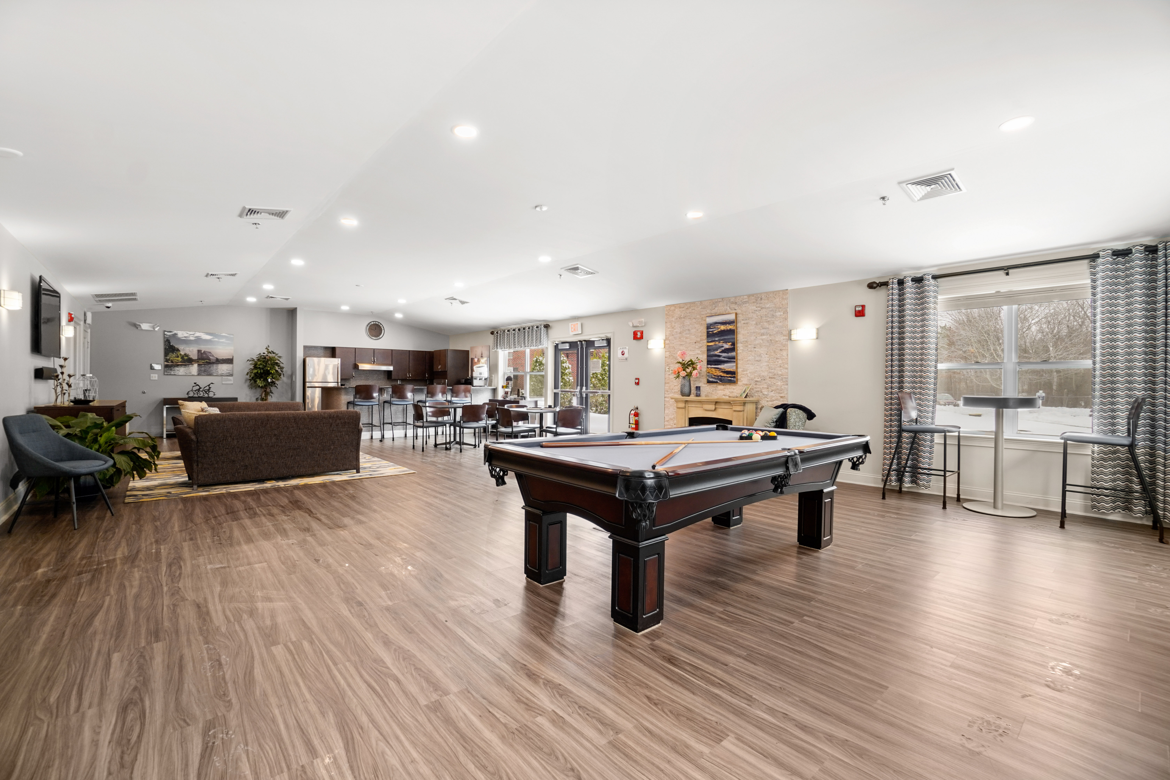 Chic open-concept community room featuring a billiards table, comfortable seating area, modern kitchen, and dining space with elegant decor.