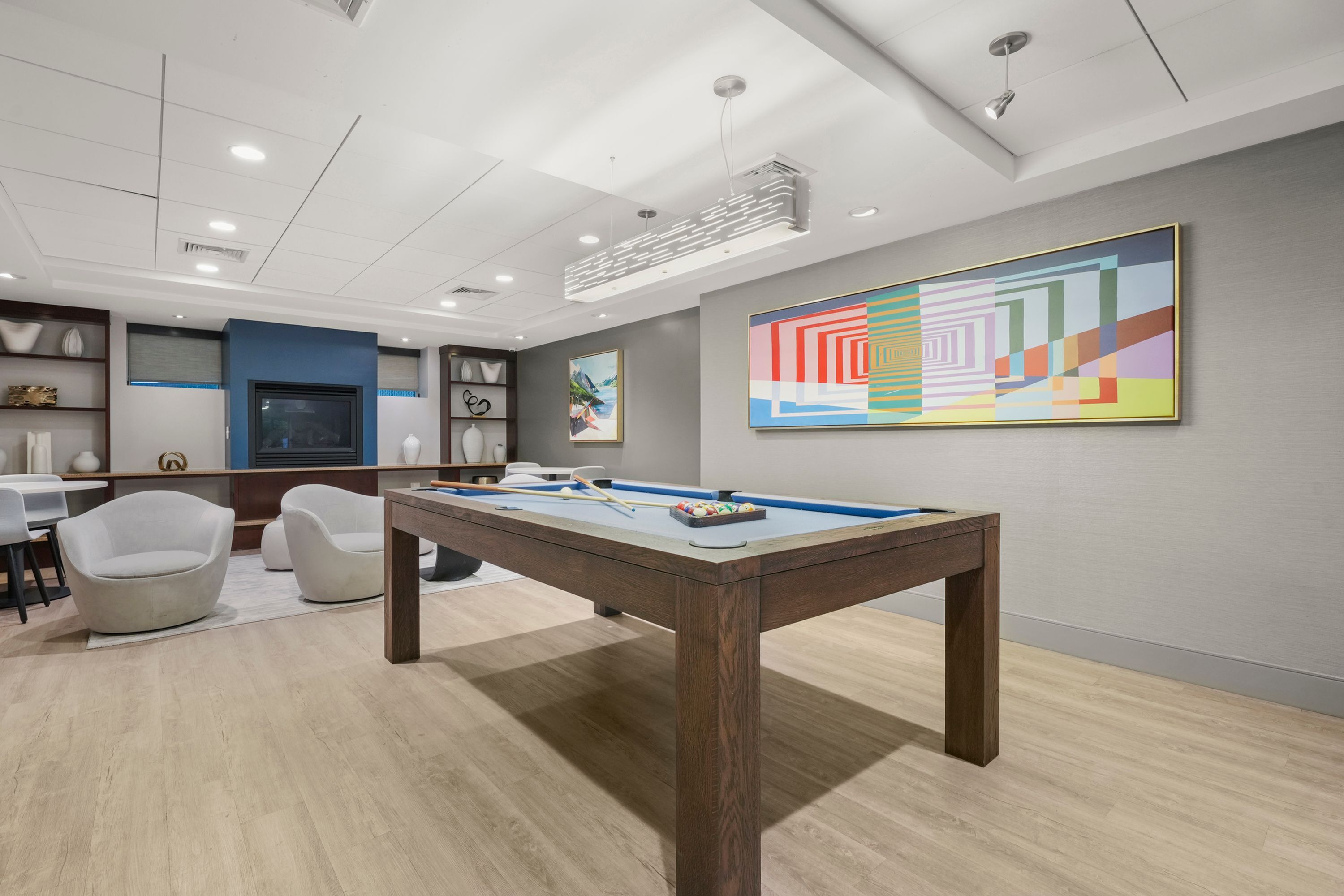 Contemporary game room featuring a stylish pool table, vibrant artwork, and cozy seating area with modern decor.