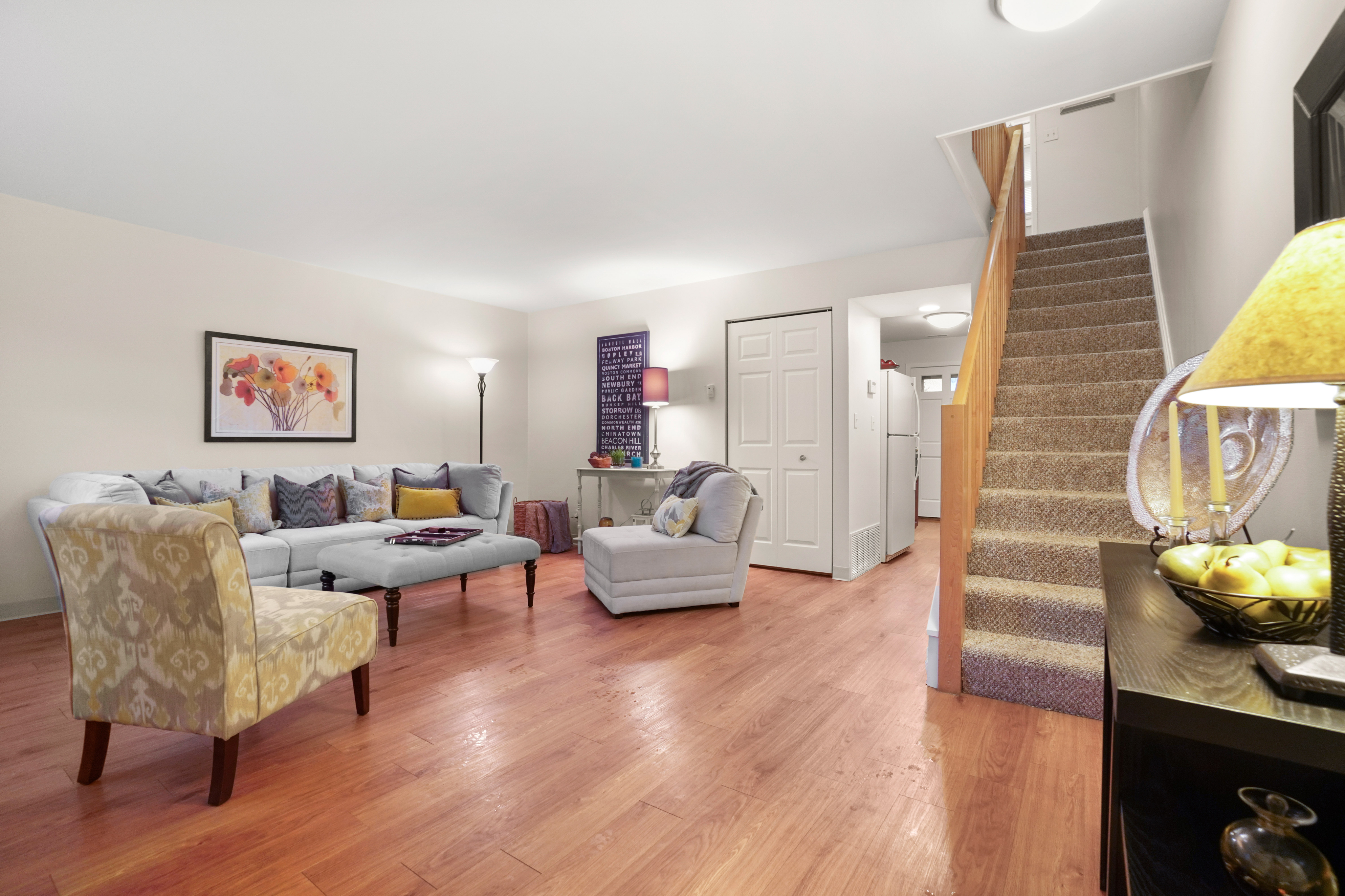 Welcoming living room with a cozy sectional sofa, elegant wooden flooring, and a modern staircase, ideal for relaxation and entertaining.