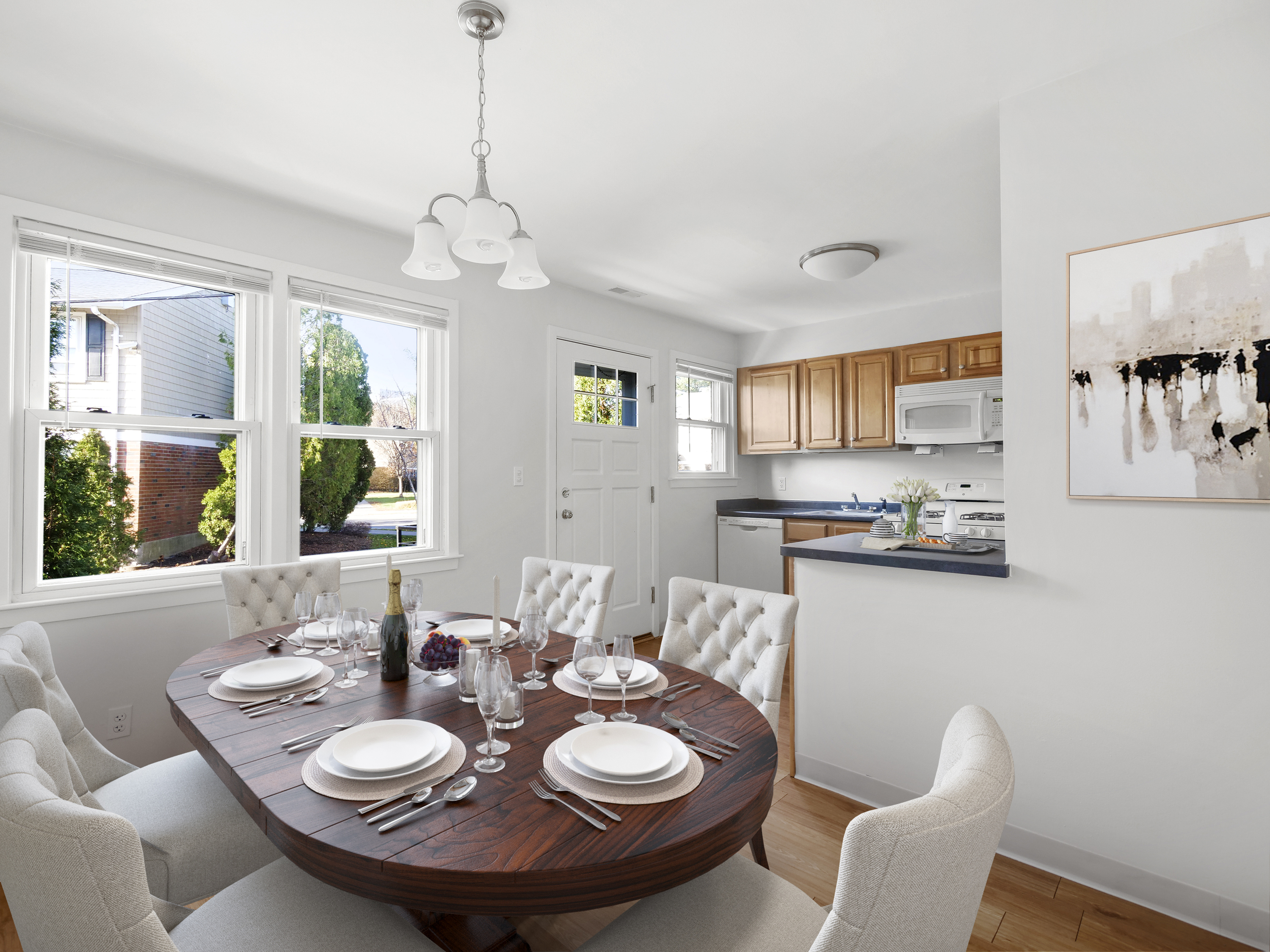Bright and inviting dining area with elegant table setting, open-concept kitchen, and large windows offering plenty of natural light.