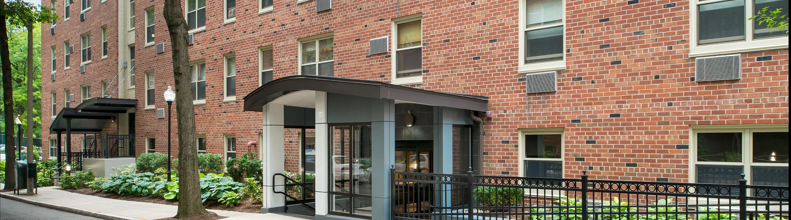 Charming urban apartment building with a welcoming entrance, surrounded by lush greenery and sleek architectural design.