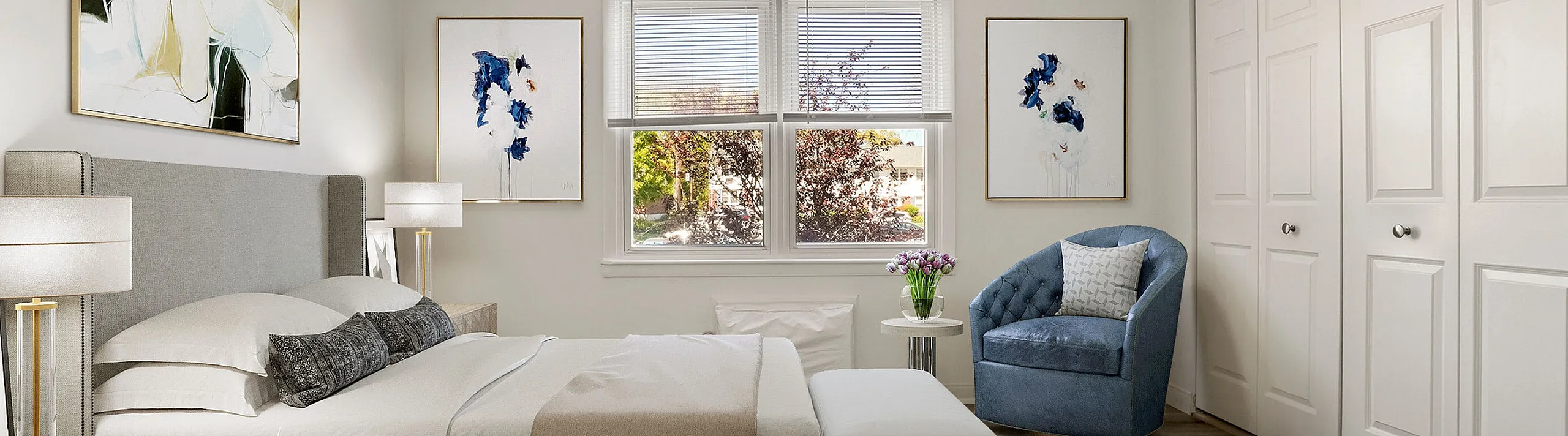Bright and modern bedroom featuring a plush bed with elegant linens, stylish armchair, and tasteful artwork, surrounded by large windows and spacious closets.