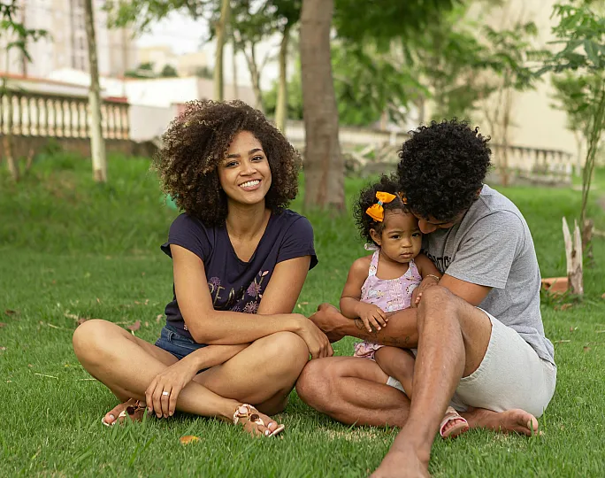 Happy family enjoying quality time together on lush green grass in a serene park setting.