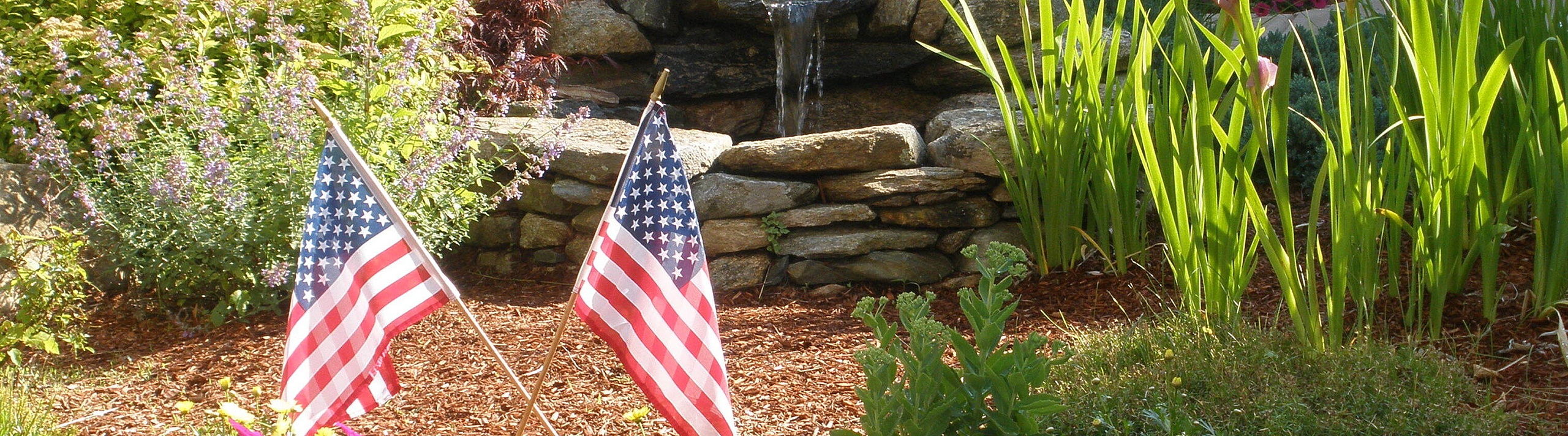 Charming garden oasis with vibrant flowers, lush greenery, and a peaceful stone water feature.