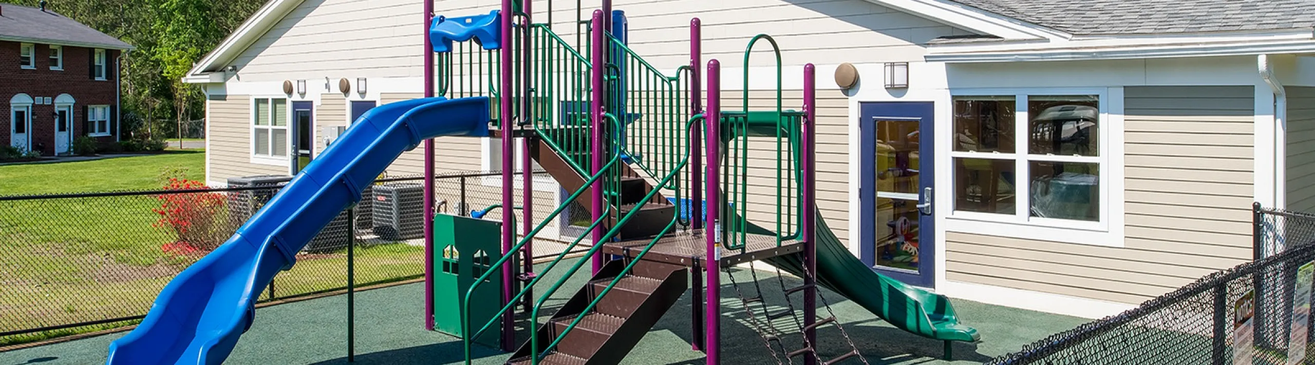 Inviting outdoor playground with vibrant slides and climbing structures, adjacent to a charming community building.