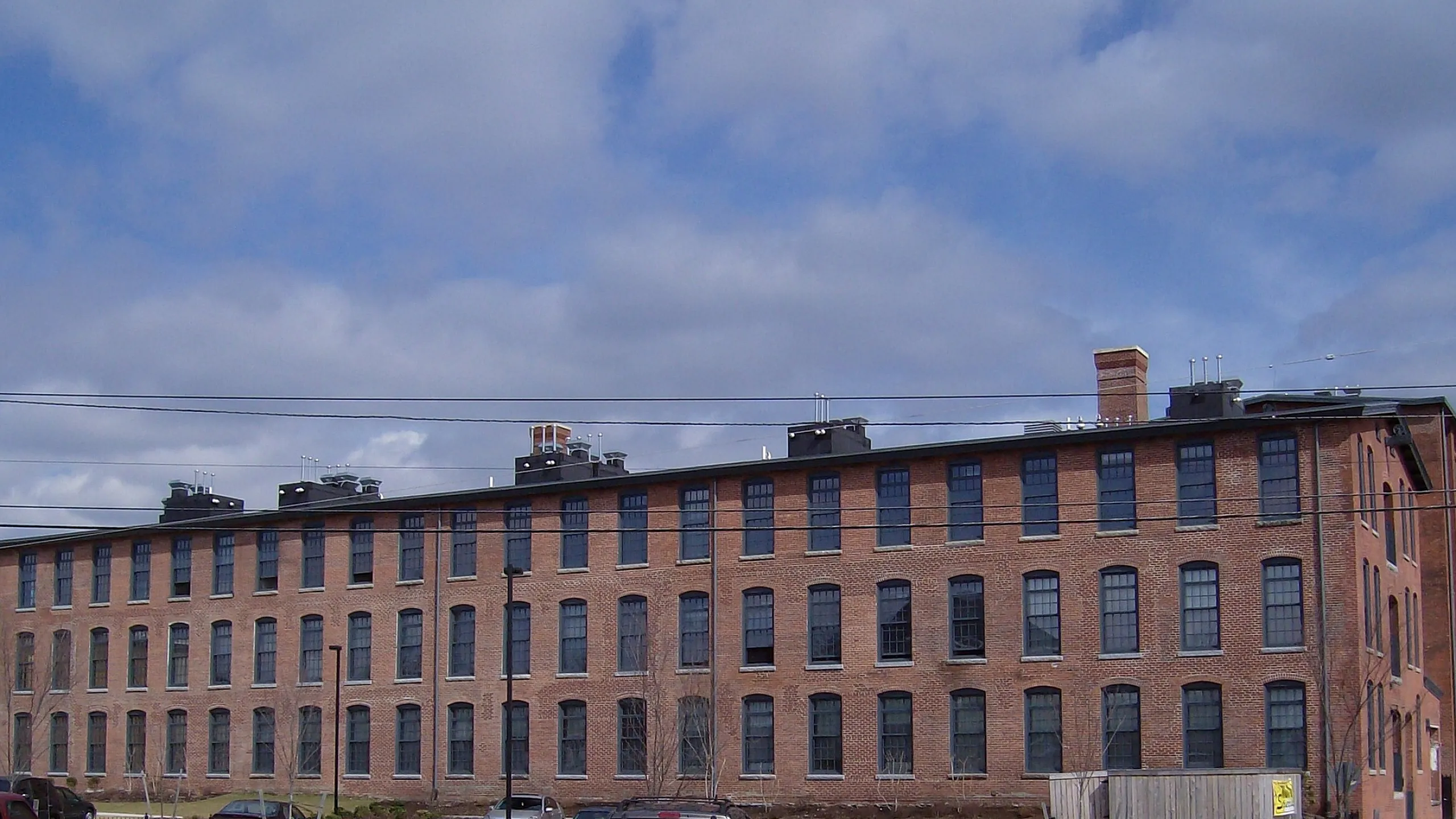 Charming historic brick building with large windows, perfect for modern loft apartments, set against a vibrant blue sky.