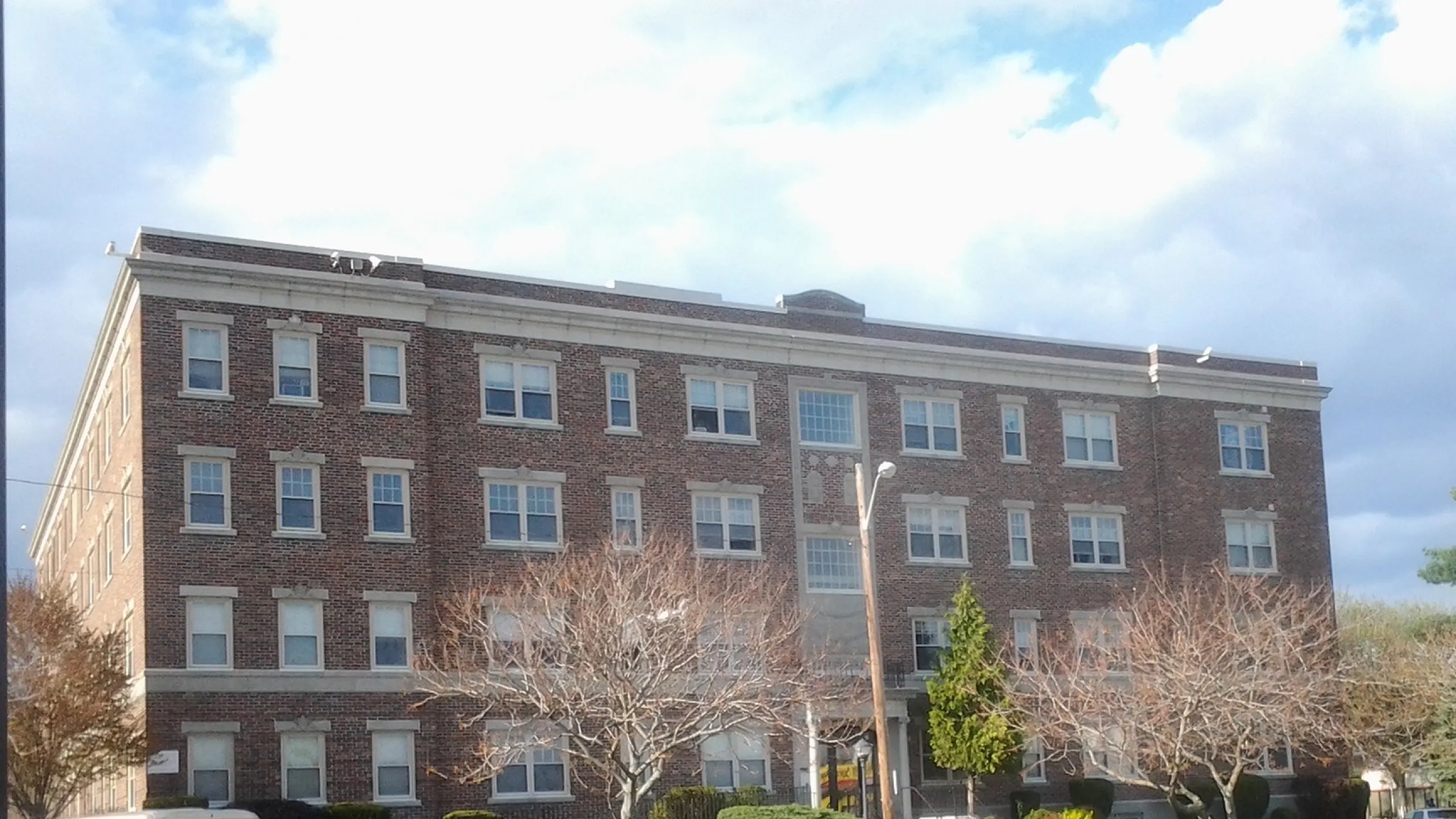 Charming brick apartment building with well-maintained landscaping and elegant facade, perfect for urban living.