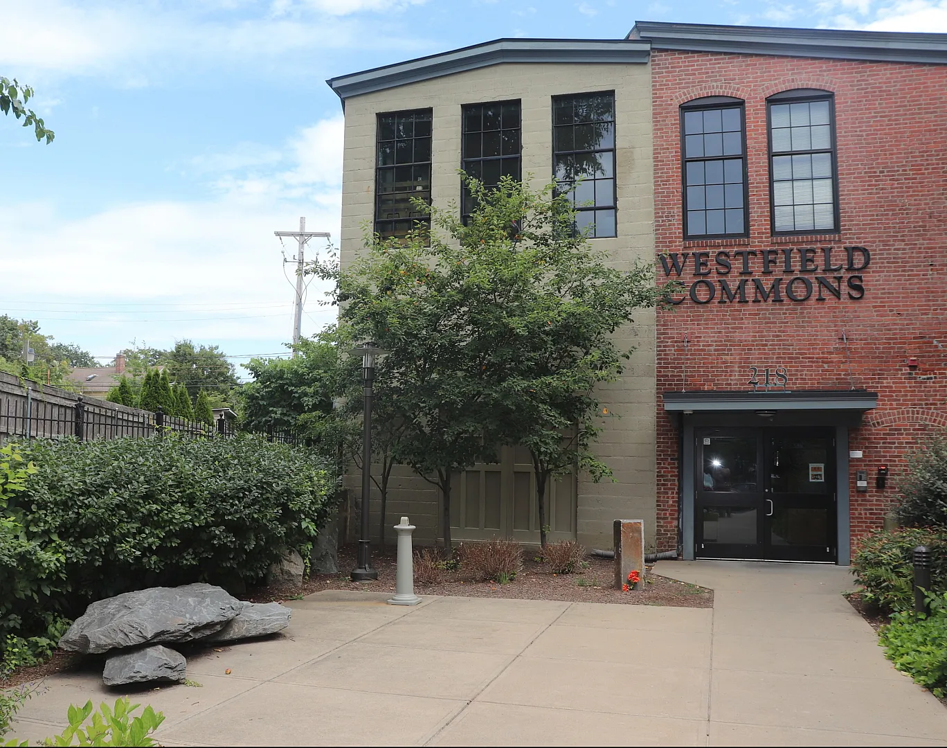 Charming brick facade of Westfield Commons with lush greenery, showcasing a welcoming community entrance.