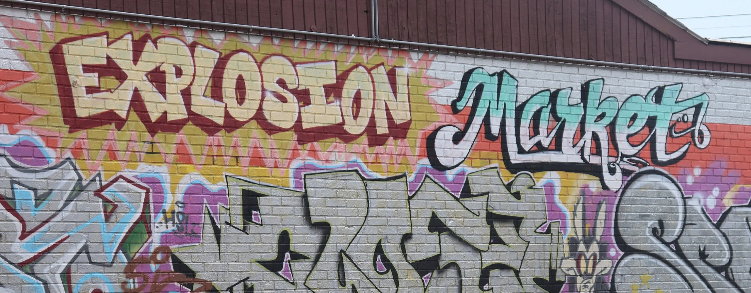 Vibrant graffiti mural featuring colorful lettering and dynamic designs on a brick wall.