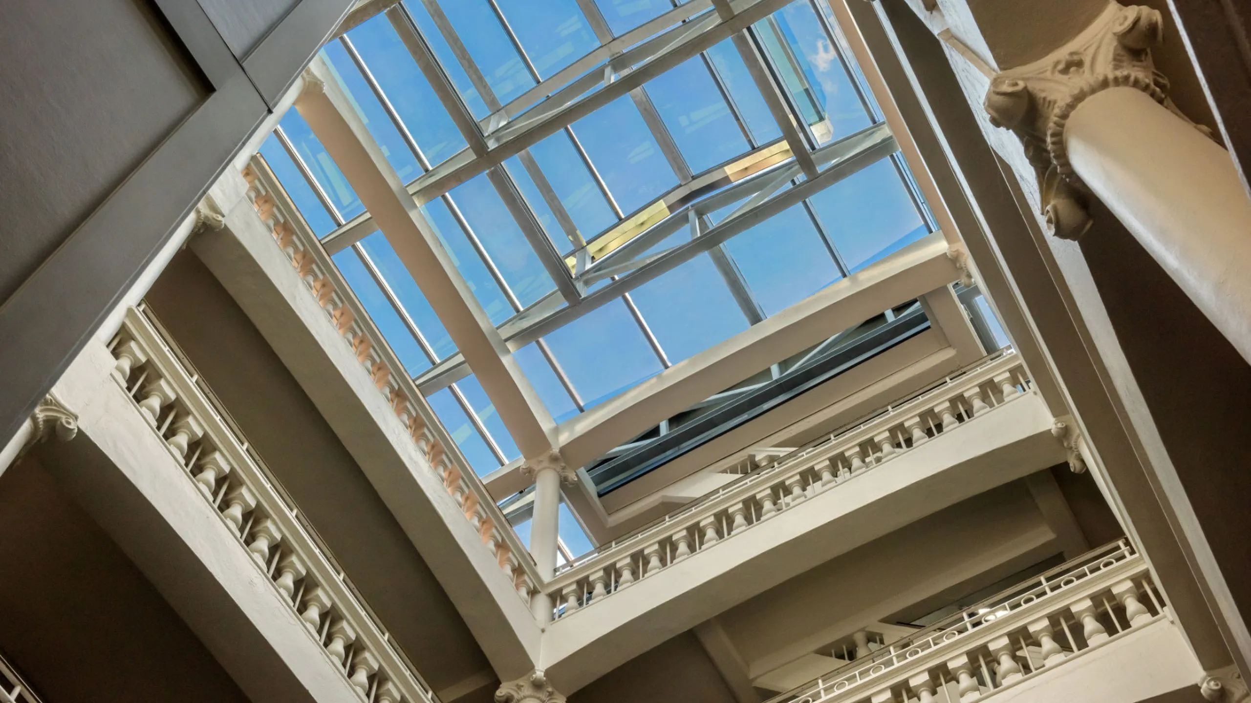 Elegant interior view of a multi-level atrium with classic architectural details and a stunning glass ceiling allowing abundant natural light.