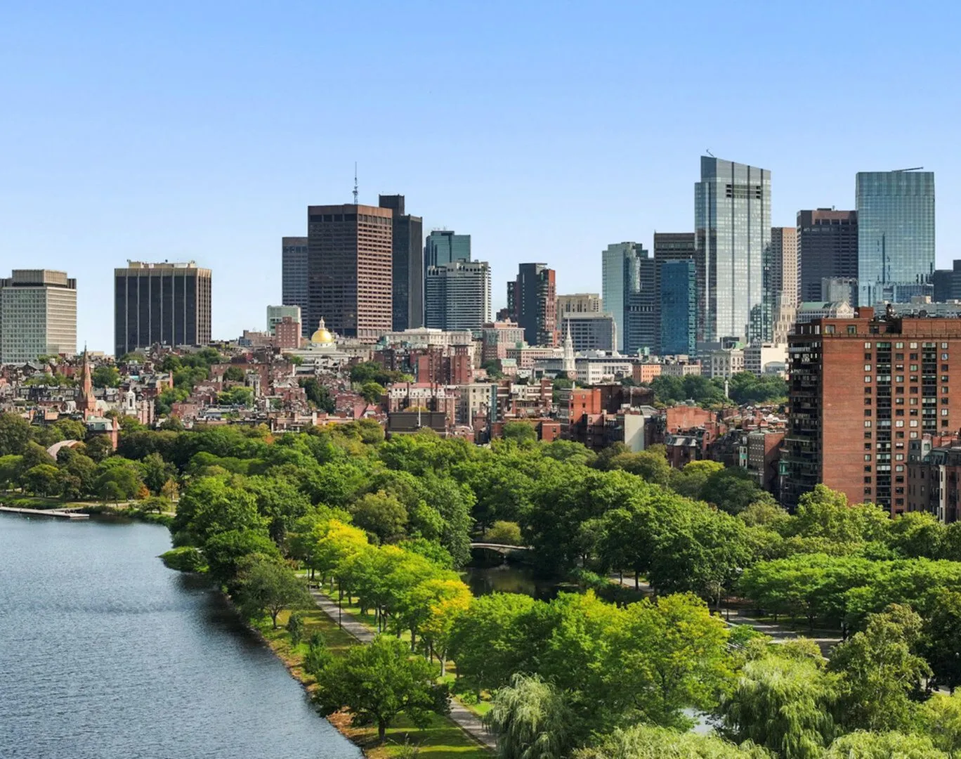 Vibrant cityscape featuring lush greenery set against a backdrop of modern skyscrapers and historic architecture by the waterfront.