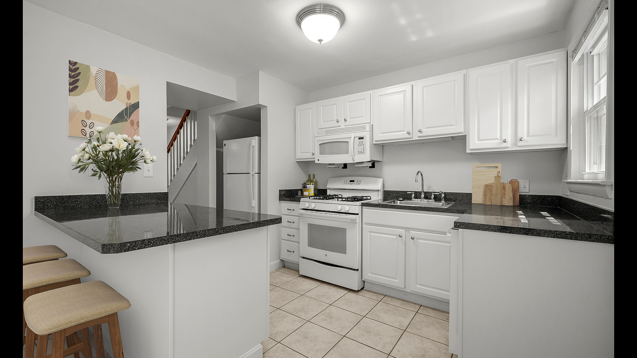 Bright and airy kitchen with modern white cabinetry, sleek granite countertops, and a cozy breakfast bar with seating.