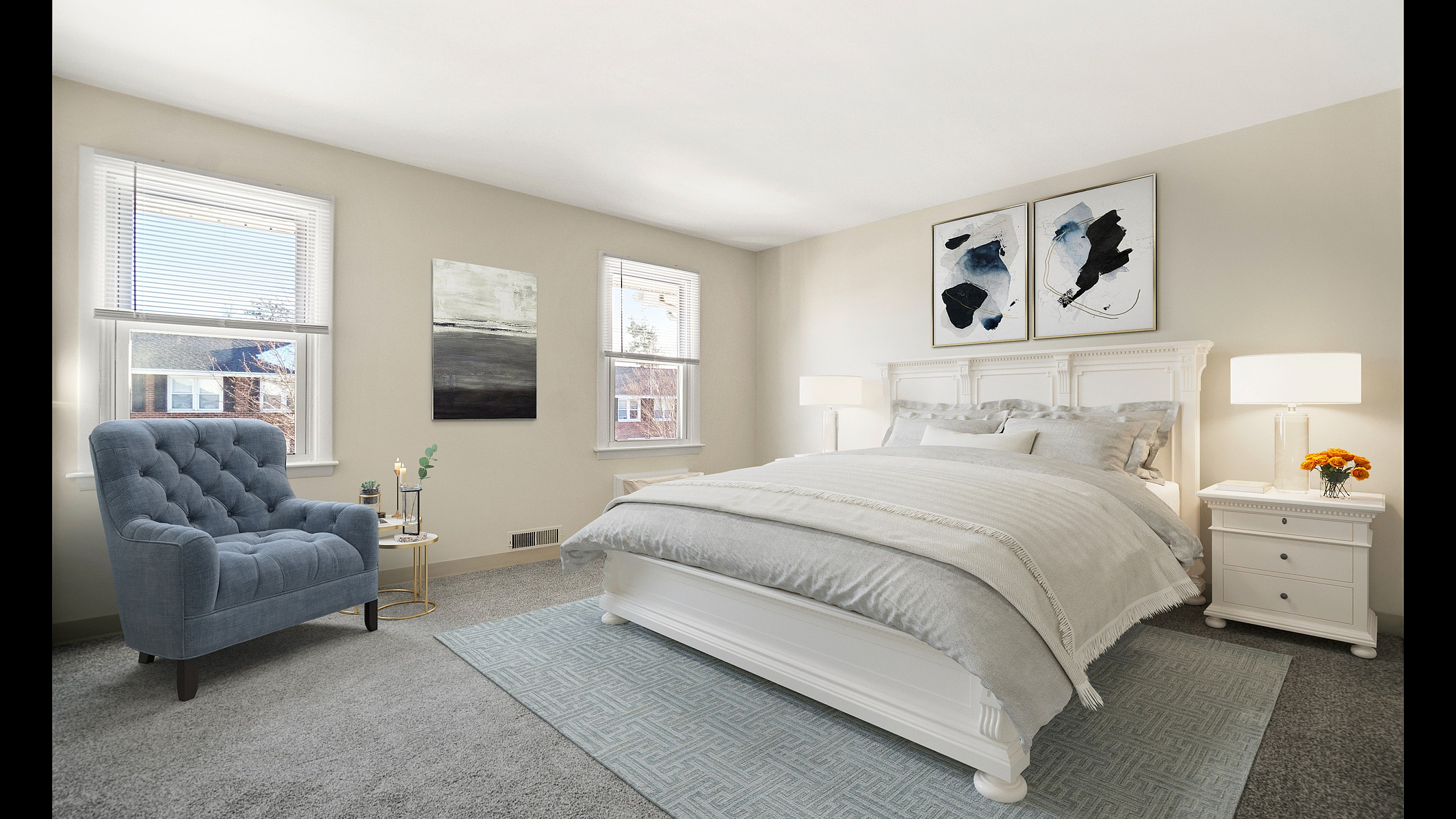 Bright and inviting bedroom with elegant white furnishings, cozy gray bedding, and a plush blue armchair, complemented by modern art and abundant natural light.