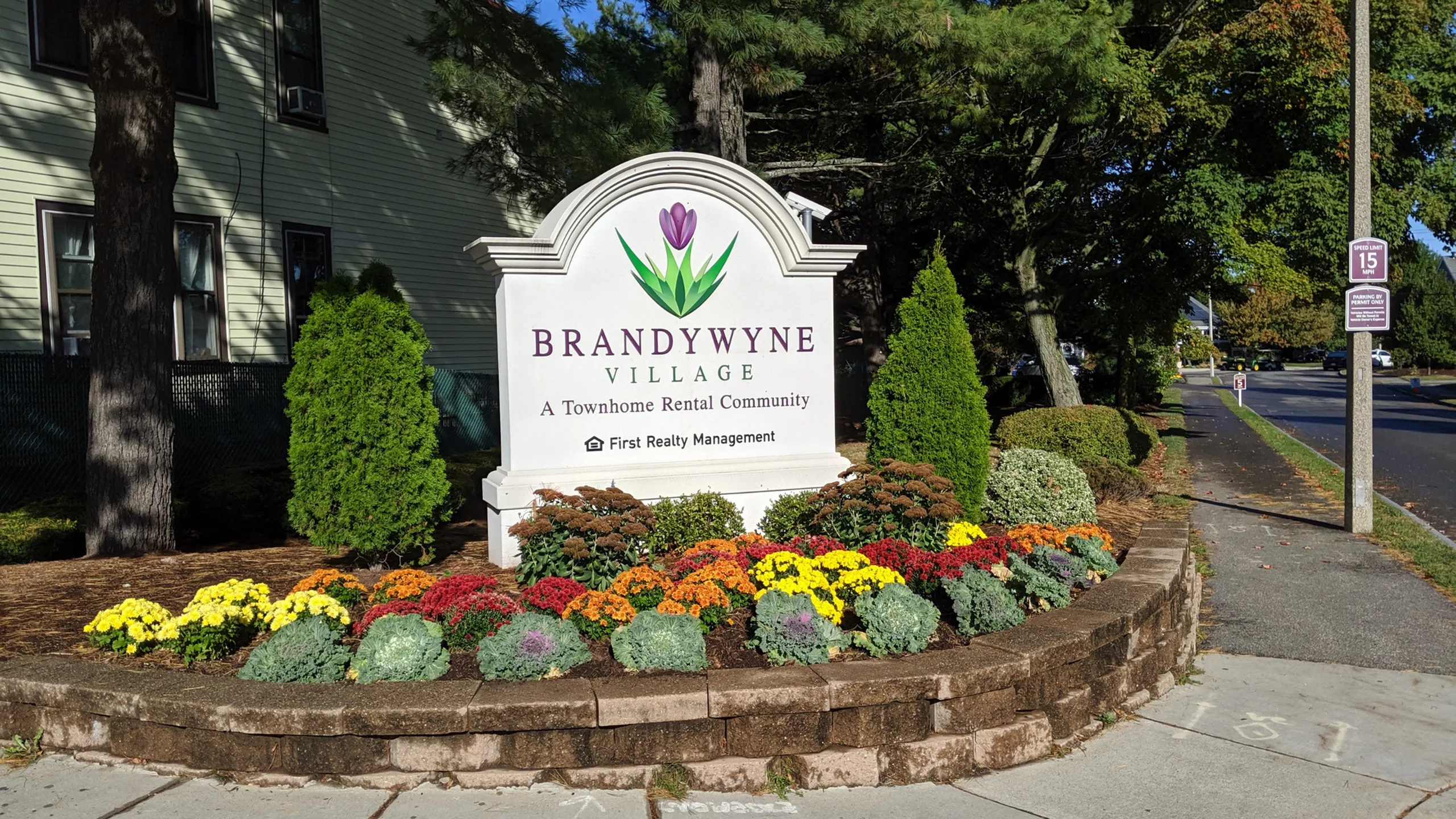 Welcoming entrance to Brandywyne Village, a vibrant townhome rental community, beautifully landscaped with colorful flower beds.