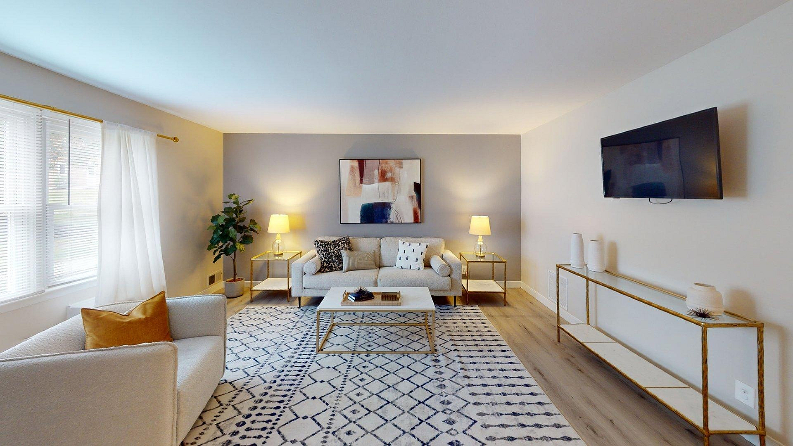 Bright and inviting living room with stylish decor, featuring a cozy beige sofa, modern art, and ample natural light.