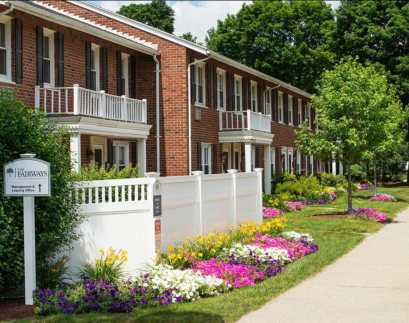 Charming brick apartments with vibrant floral landscaping and inviting front porches at The Fairways.