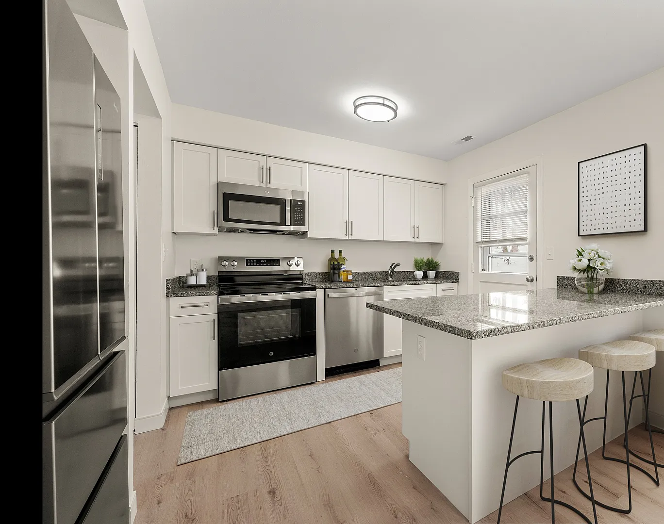 Modern kitchen featuring sleek granite countertops, stainless steel appliances, and a cozy breakfast bar with elegant stools, creating a stylish and inviting space.