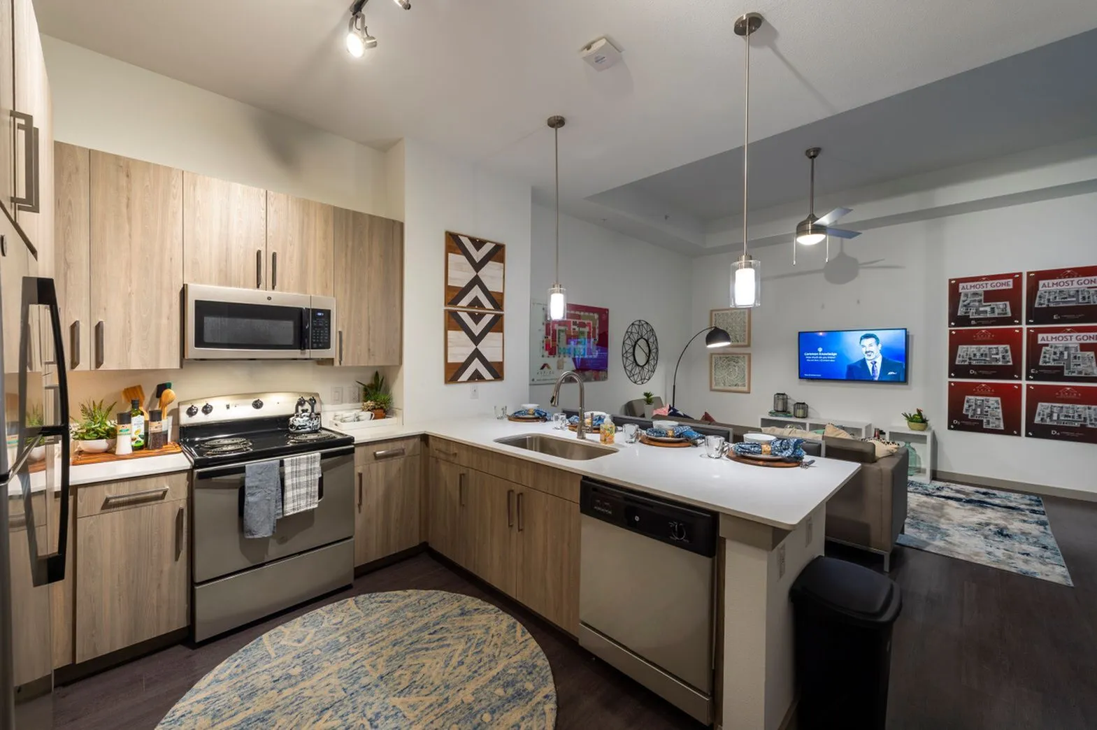Modern kitchen with sleek appliances, pendant lighting, and an open-concept design leading into a cozy living area, perfect for entertaining.