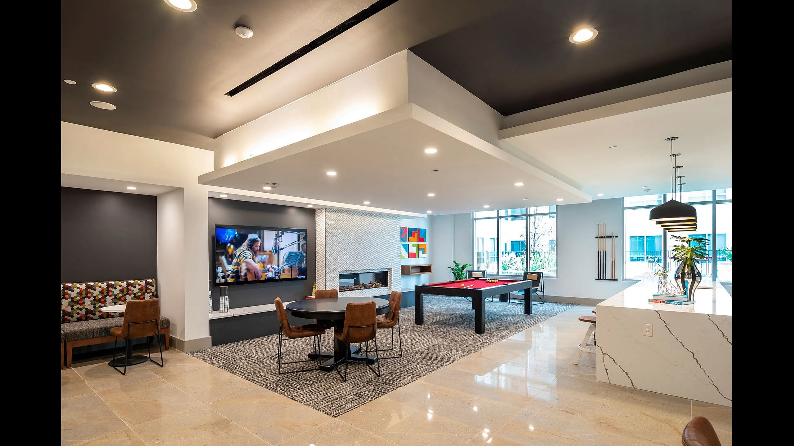 Luxurious modern apartment lounge with pool table, stylish seating, and large TV for entertainment, enhanced by natural light and elegant decor.