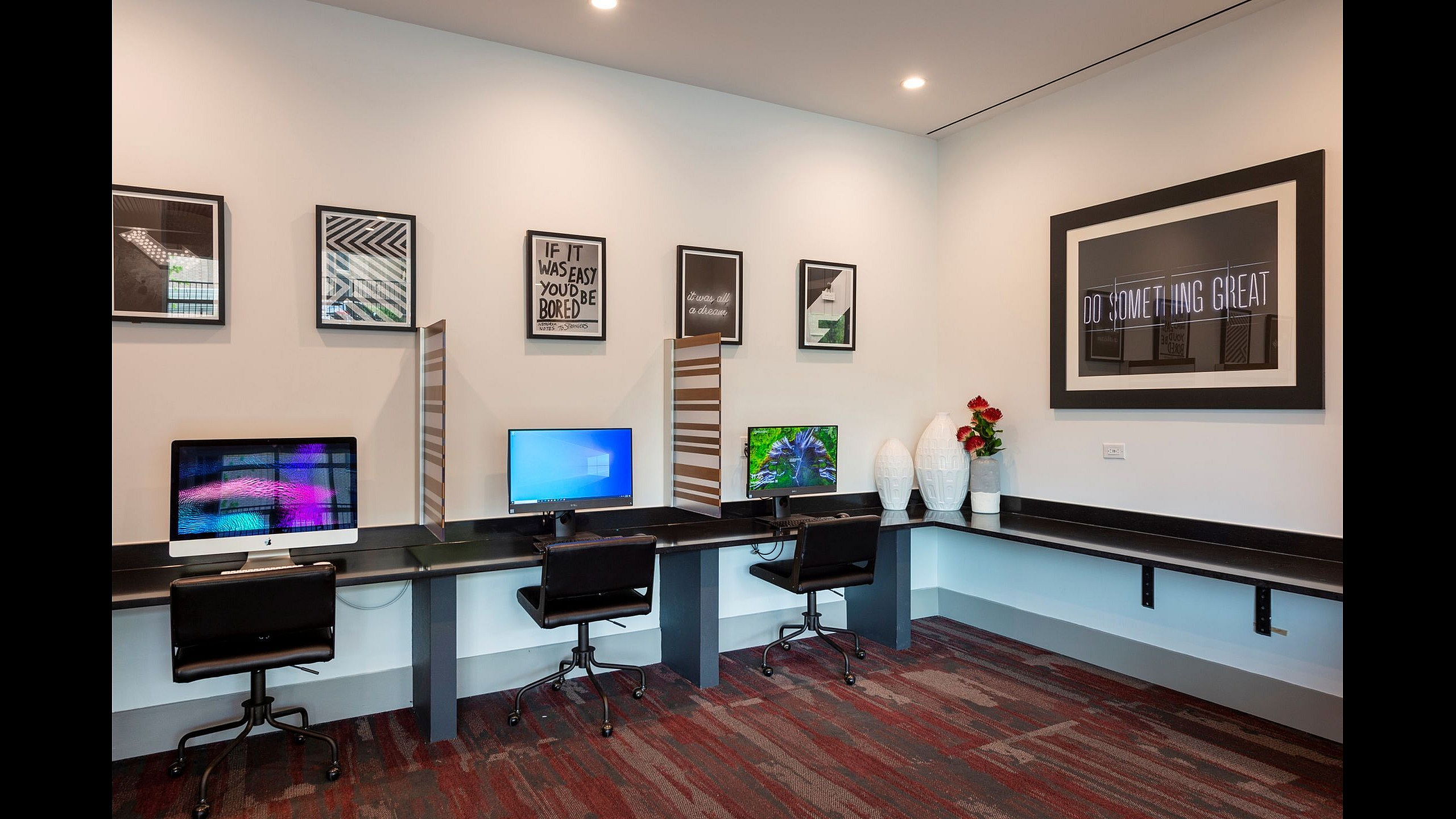 Sleek and modern workspace with three computer stations, stylish decor, and motivational artwork, perfect for productivity and inspiration.