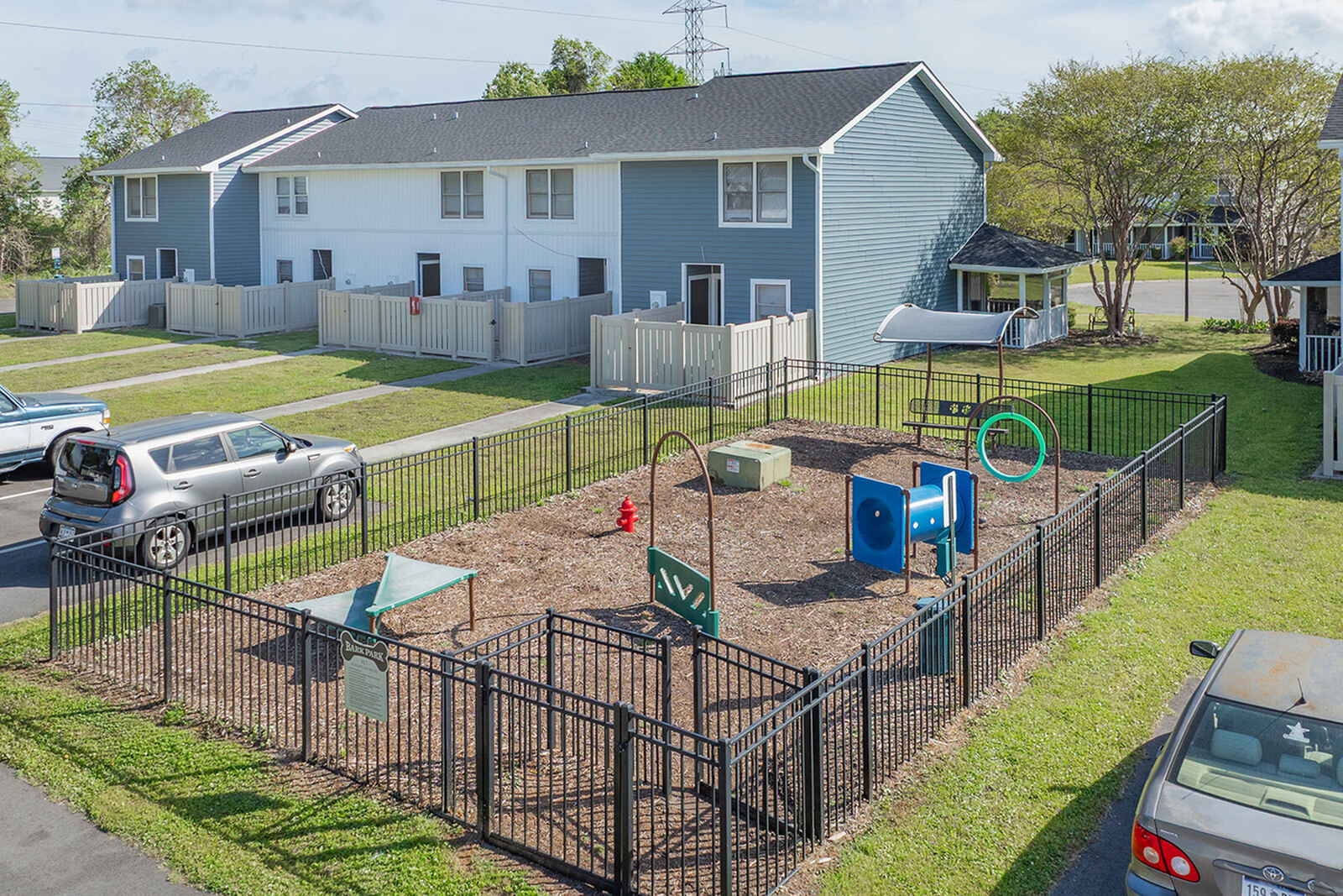 Charming residential community with vibrant playground, secure fencing, and modern townhouses surrounded by lush greenery.
